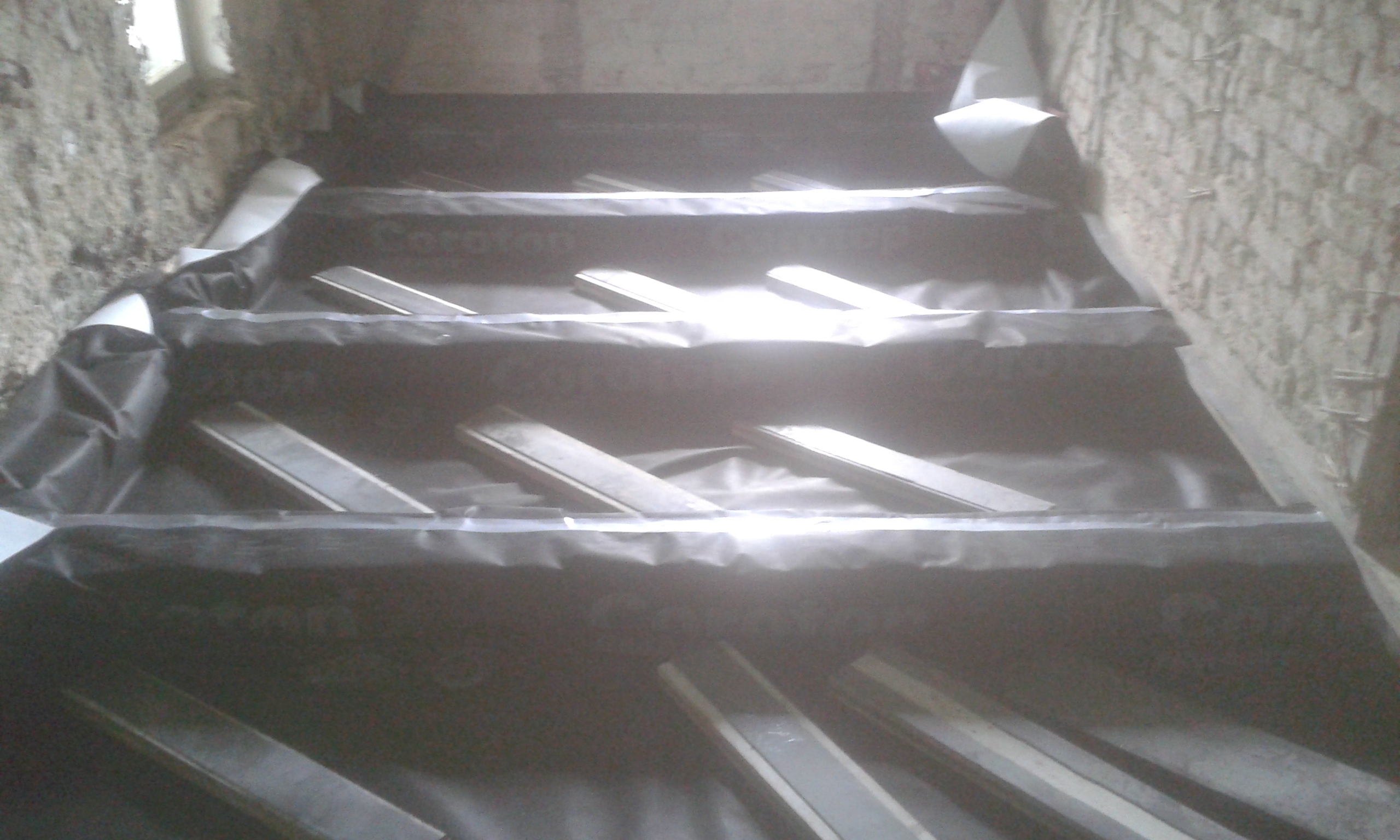 Widok na strop poddasza z ułożoną paroizolacją i elementami konstrukcyjnymi, przygotowany do montażu kolejnych warstw podłog