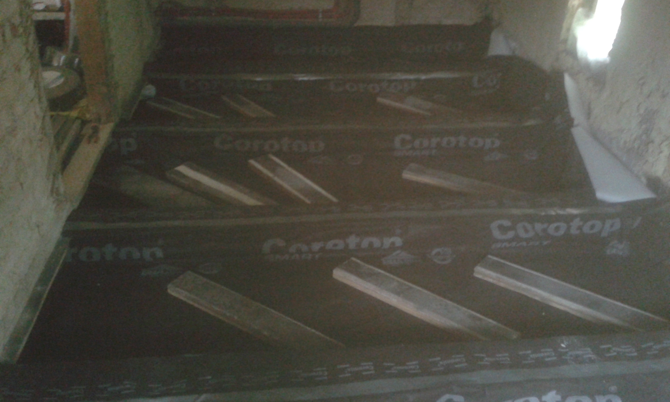 Strop poddasza zabezpieczony warstwą paroizolacyjną, widoczne elementy konstrukcyjne oraz przygotowanie powierzchni pod dalsze etapy prac podłogowych.