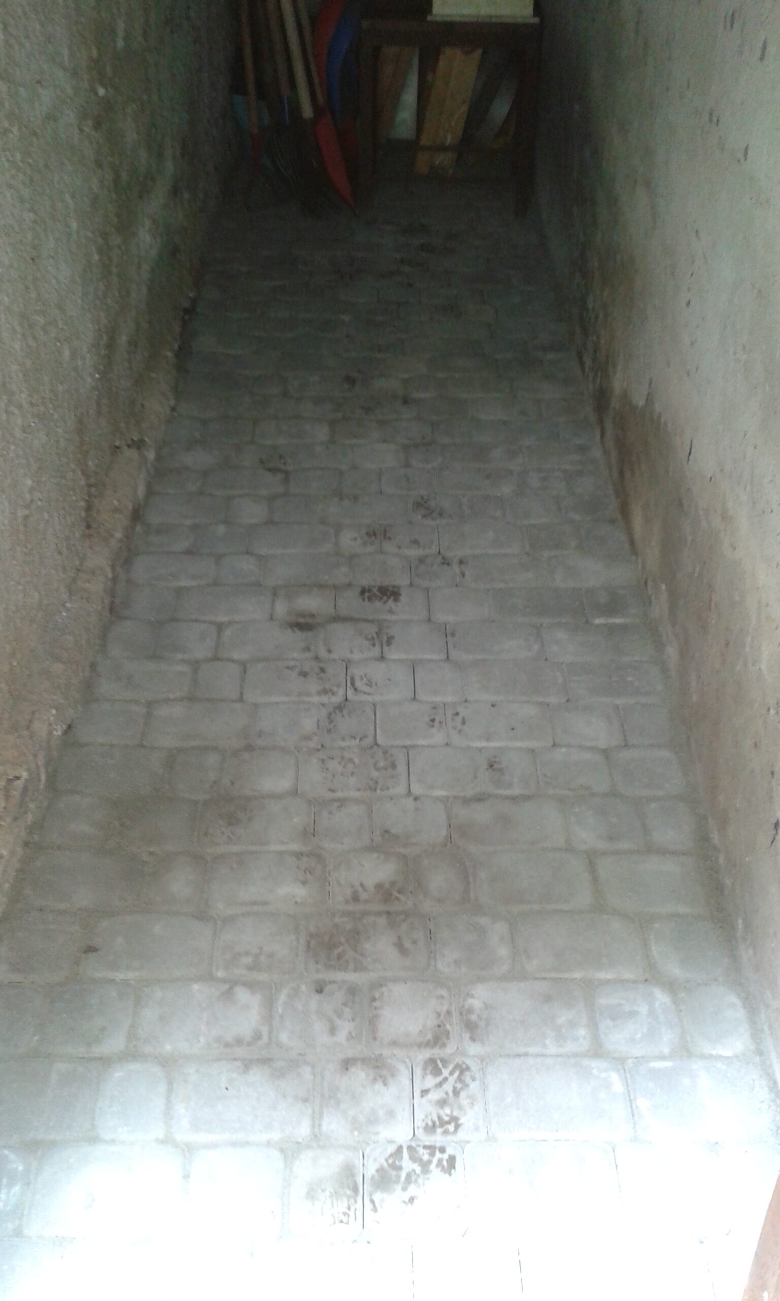 Wąskie pomieszczenie z nowo ułożoną kostką brukową na podłodze, pokazujące równy układ elementów i estetyczne wykończenie nawierzchni.