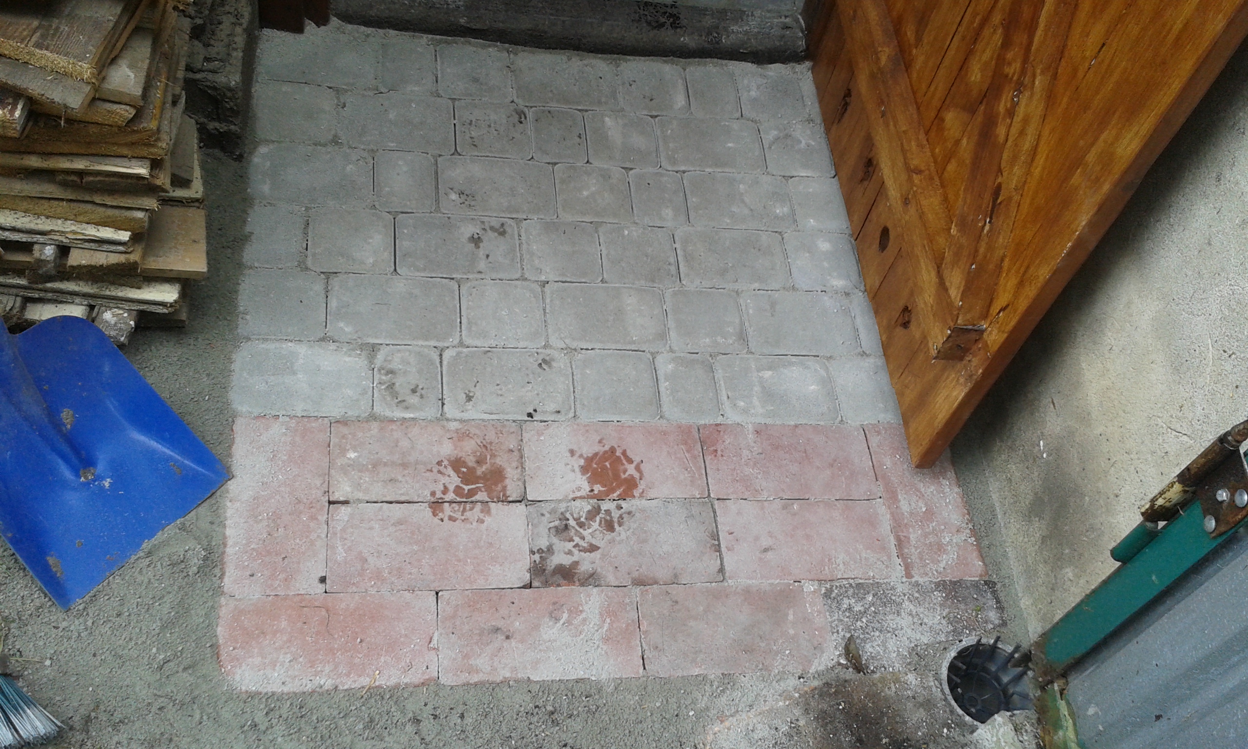 Fragment świeżo ułożonej kostki brukowej przy wejściu do pomieszczenia, z wyraźnym podziałem kolorystycznym i równym układem elementów.