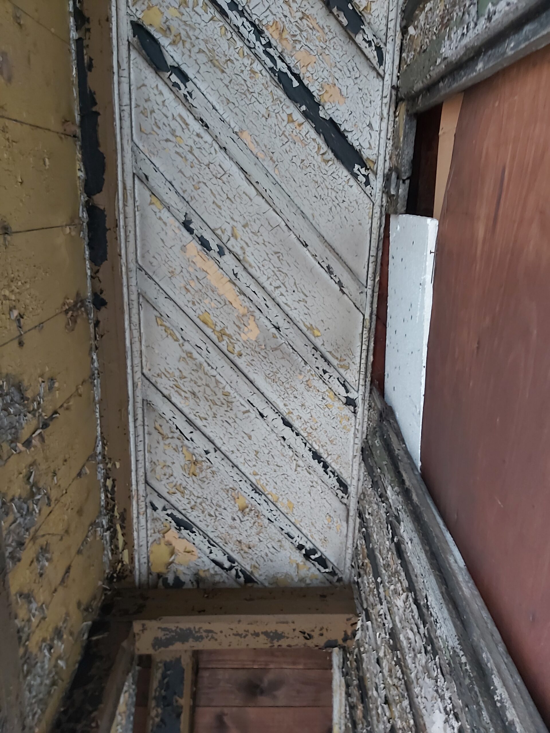 Zniszczona drewniana okładzina balkonu z łuszczącą się farbą