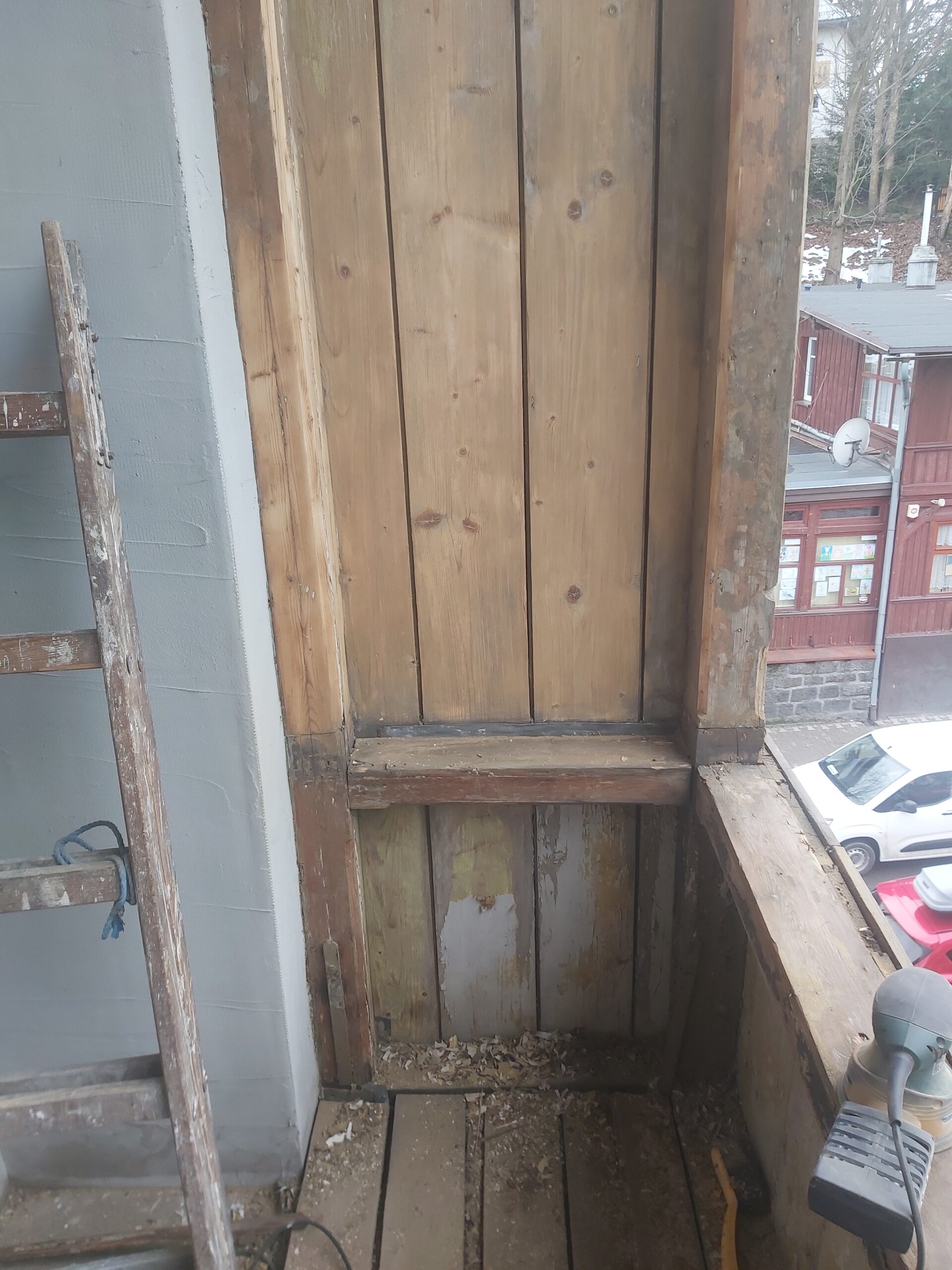 Odsłonięta pionowa zabudowa balkonu z drewnianych desek oraz elementów konstrukcyjnych, przygotowana do dalszych prac renowacyjnych.