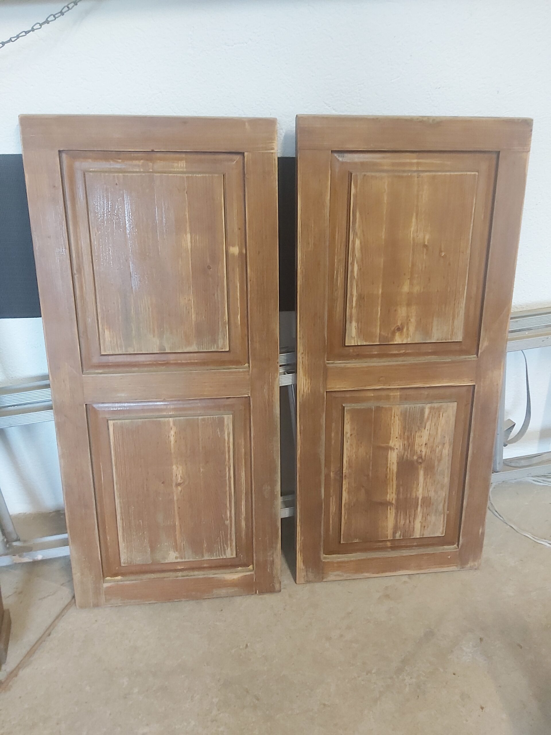 Dwa drewniane fronty meblowe ustawione pionowo obok siebie, z widocznymi śladami zużycia i nierówną powierzchnią po wcześniejszym lakierowaniu.
