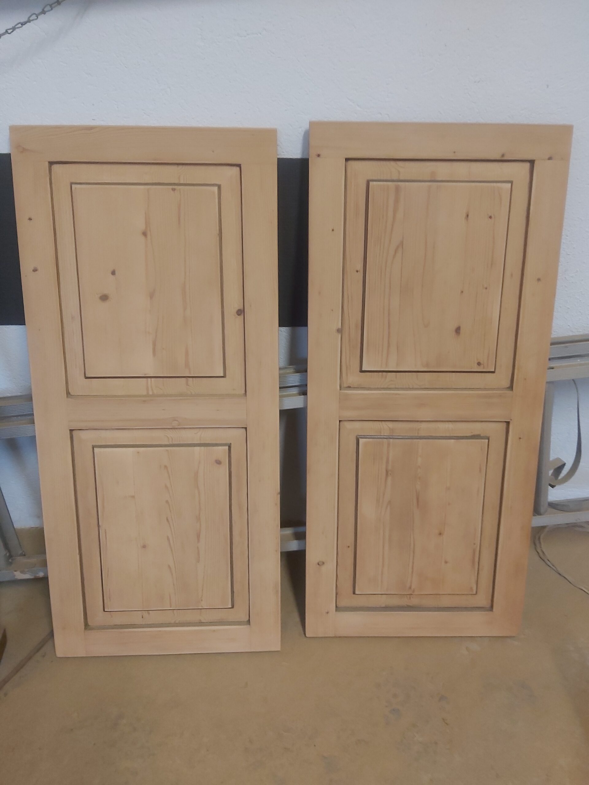 Dwa jasne, drewniane fronty meblowe ustawione pionowo obok siebie, z wyraźnym frezowaniem i naturalnym usłojeniem drewna.