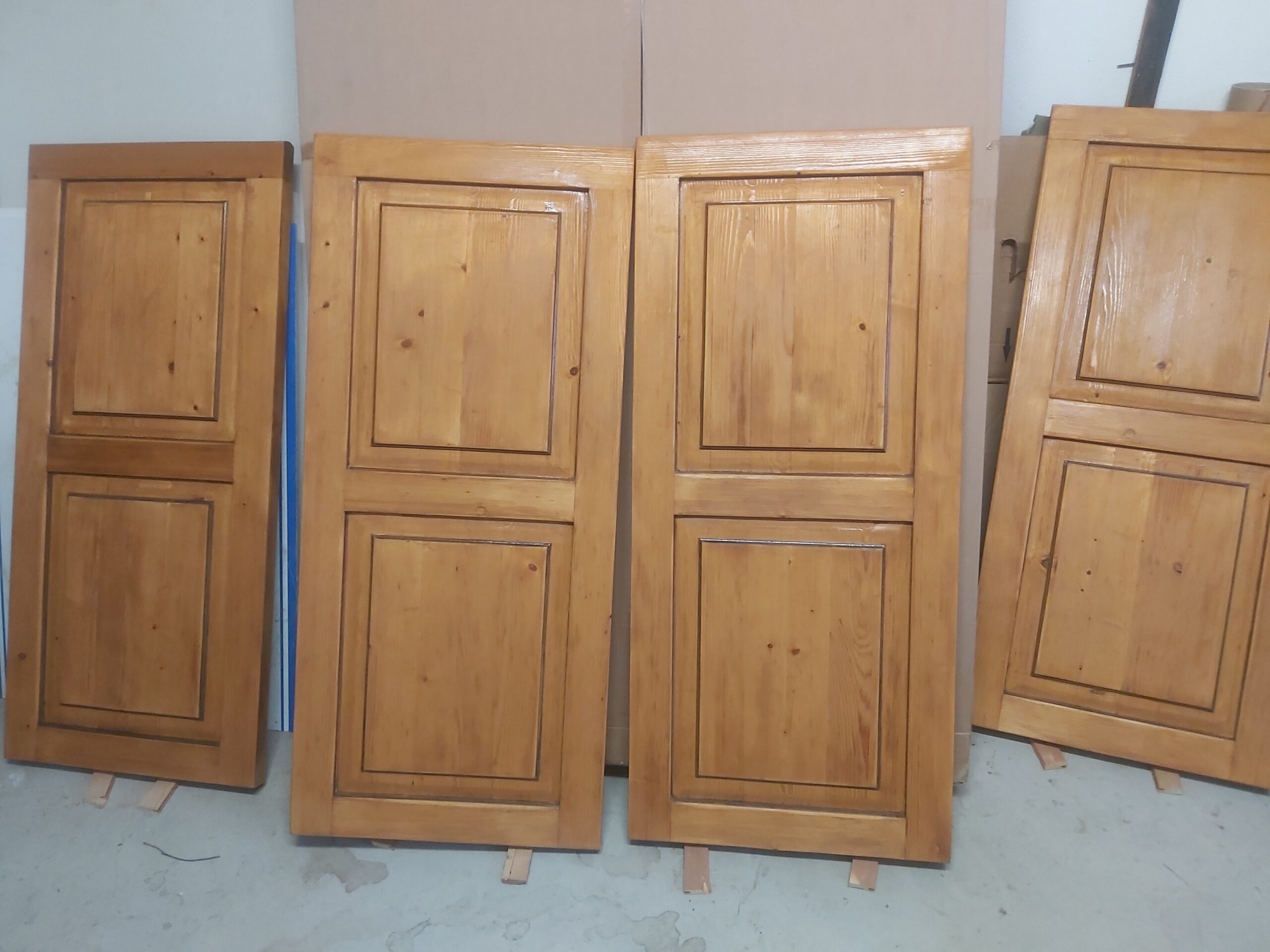 Cztery drewniane fronty meblowe ustawione pionowo obok siebie, z jednolitą, odświeżoną powierzchnią i wyraźnym rysunkiem drewna po renowacji.