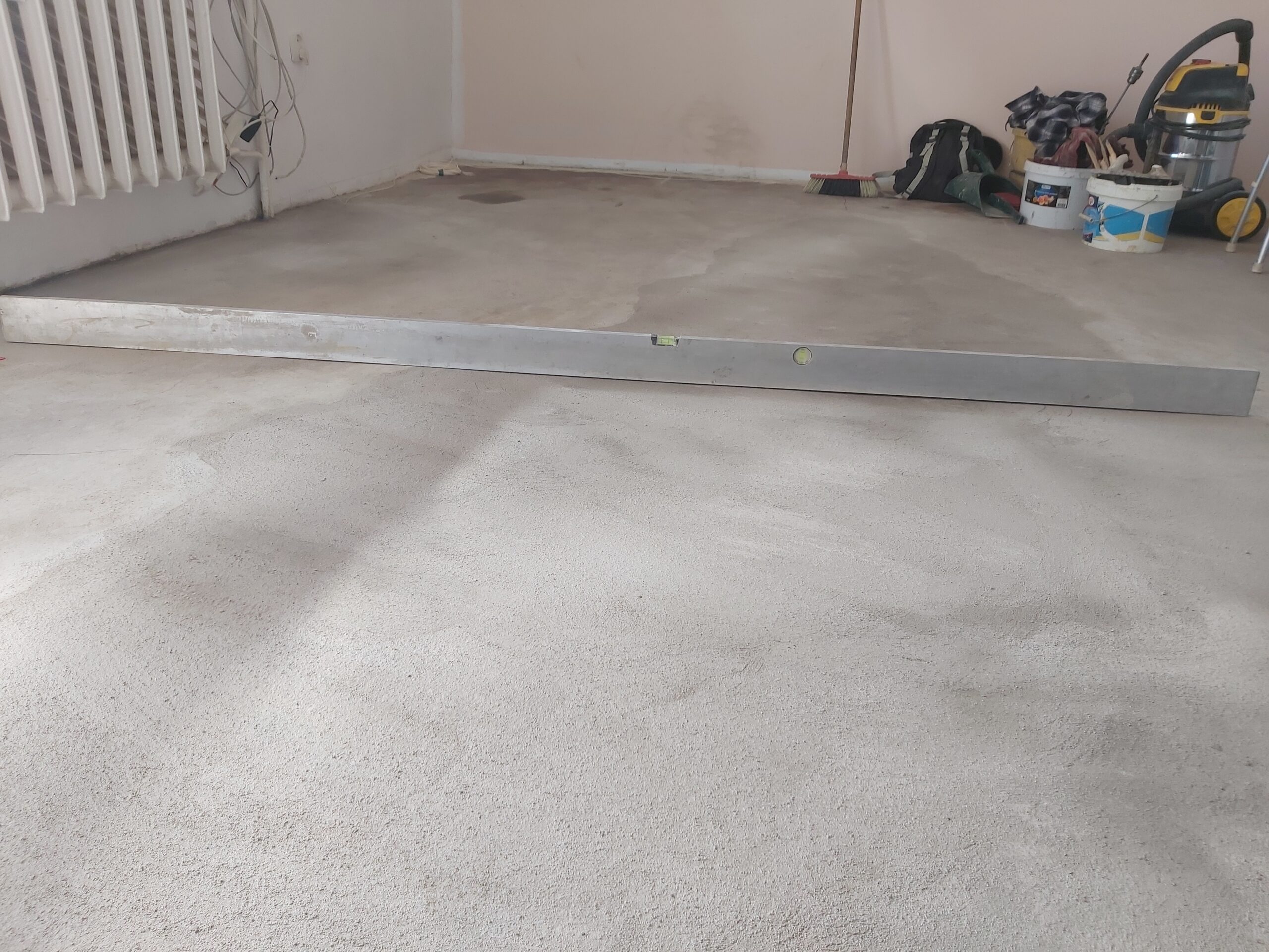 Sprawdzanie równości i poziomu posadzki przy użyciu długiej poziomicy w trakcie prac wykończeniowych.