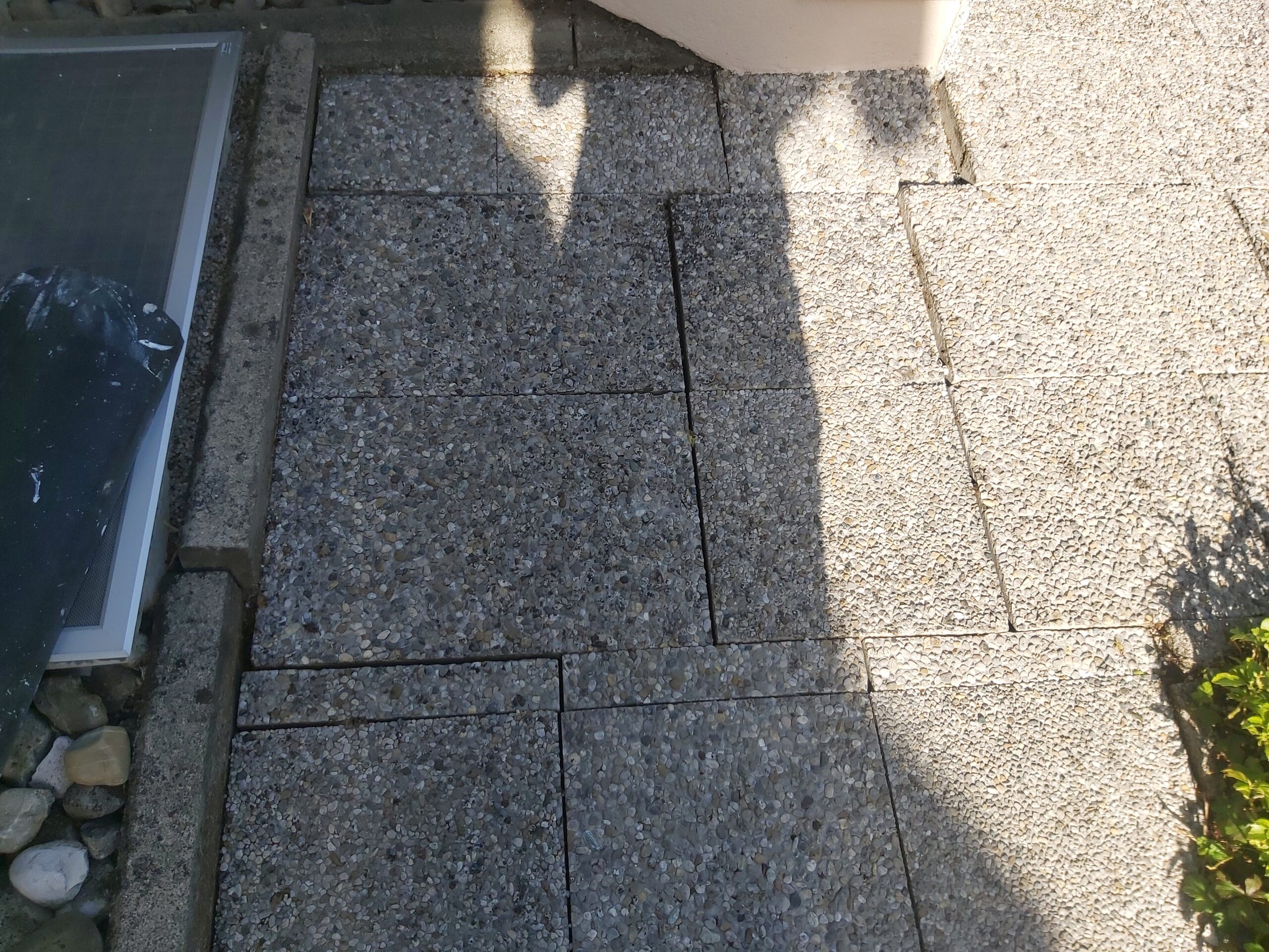 Fragment wykończonej nawierzchni z kostki brukowej przy ścianie budynku, z widocznym precyzyjnym docięciem elementów i równymi fugami.