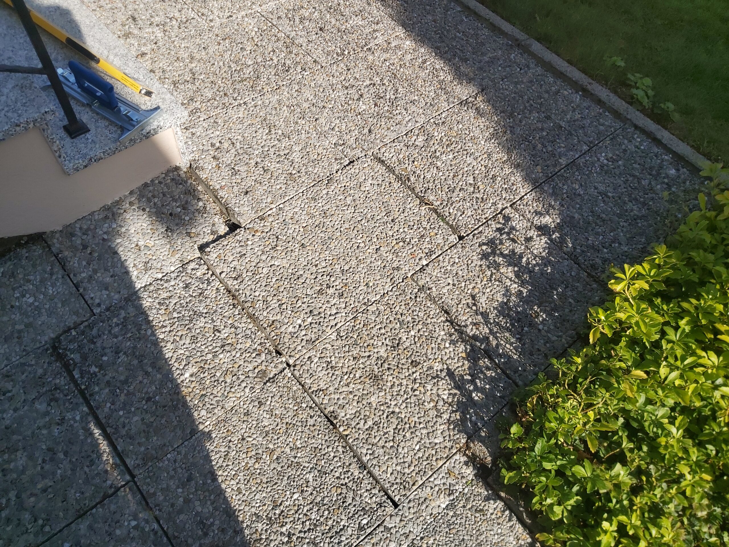 Gotowa nawierzchnia z kostki brukowej przy schodach wejściowych, z widocznymi równymi fugami i dopasowaniem do otaczającej zieleni.