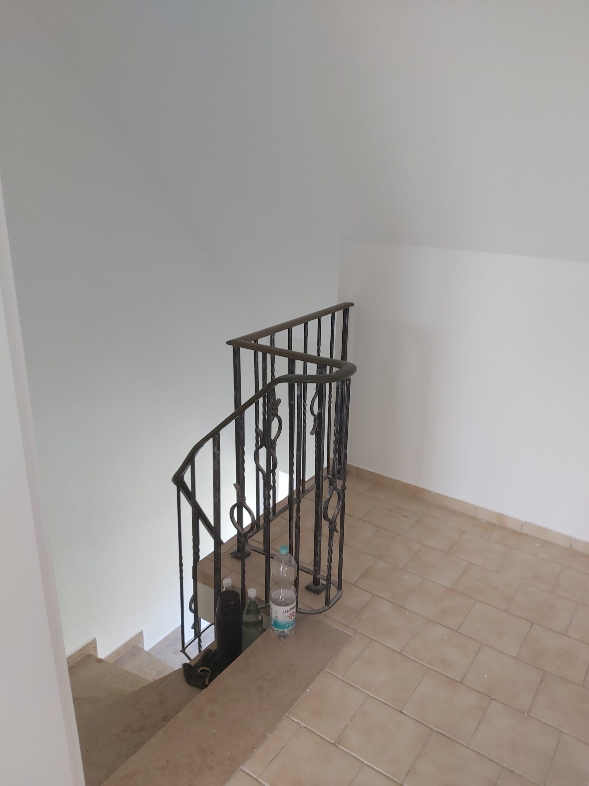 Jasna klatka schodowa po zakończonym malowaniu, z odnowionymi ścianami, metalową balustradą oraz schodami prowadzącymi na niższy poziom.