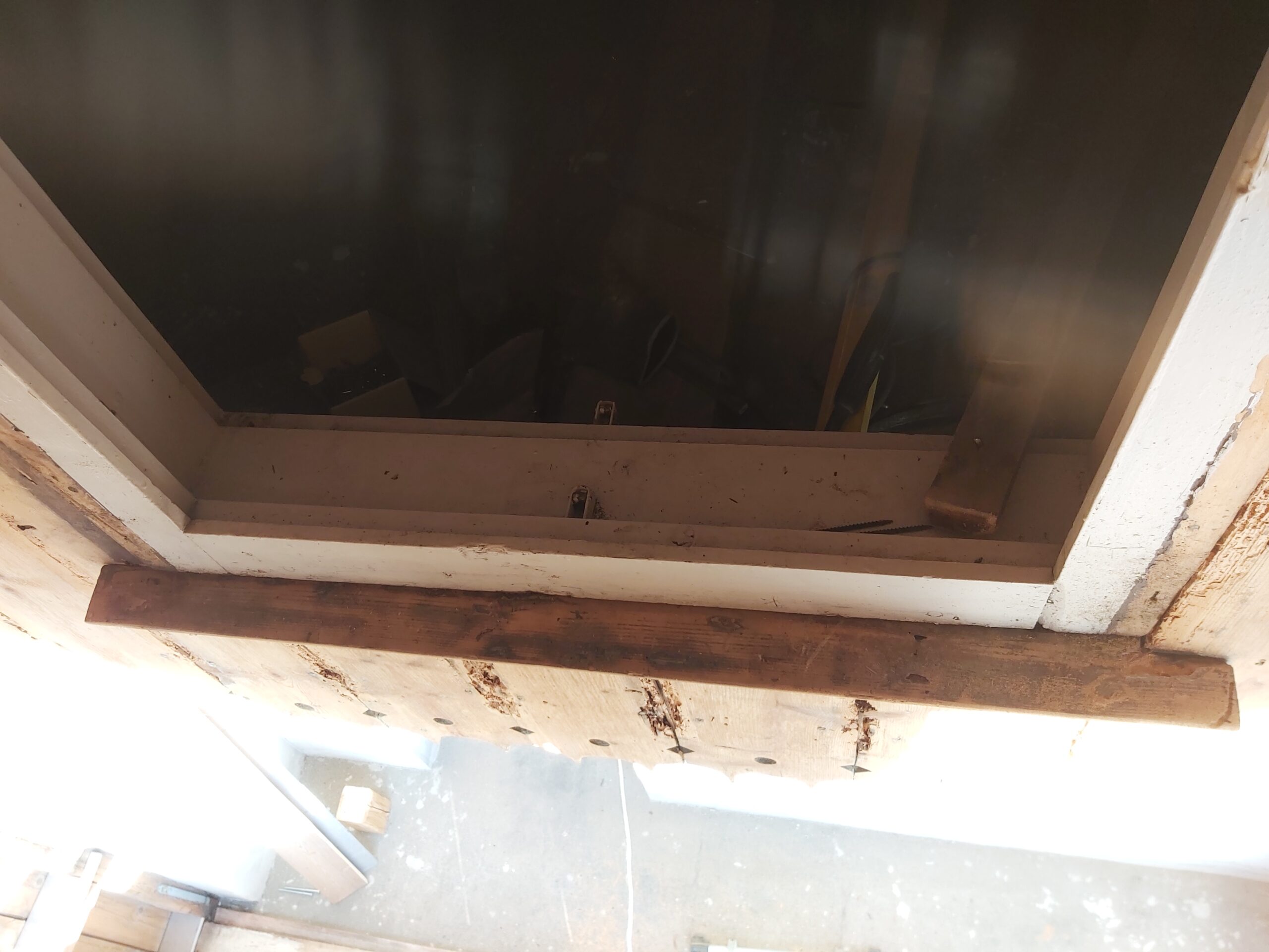 Zbliżenie na dolną krawędź okna od wewnątrz, z widoczną drewnianą listwą montażową i elementami konstrukcyjnymi podczas prac wykończeniowych balkonu.