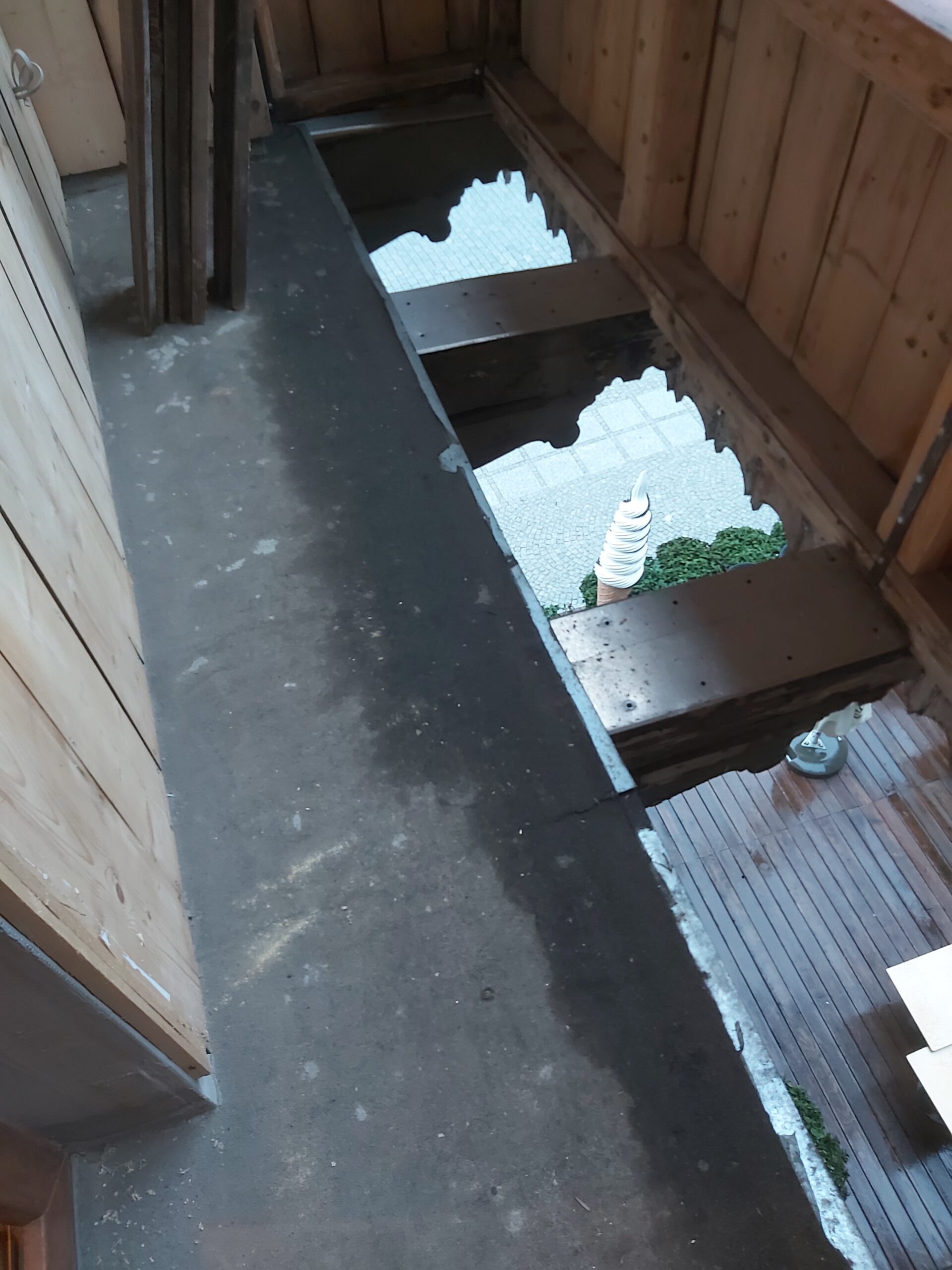 Odsłonięta podłoga balkonu z widocznymi belkami nośnymi i otwartą przestrzenią pod konstrukcją podczas remontu.