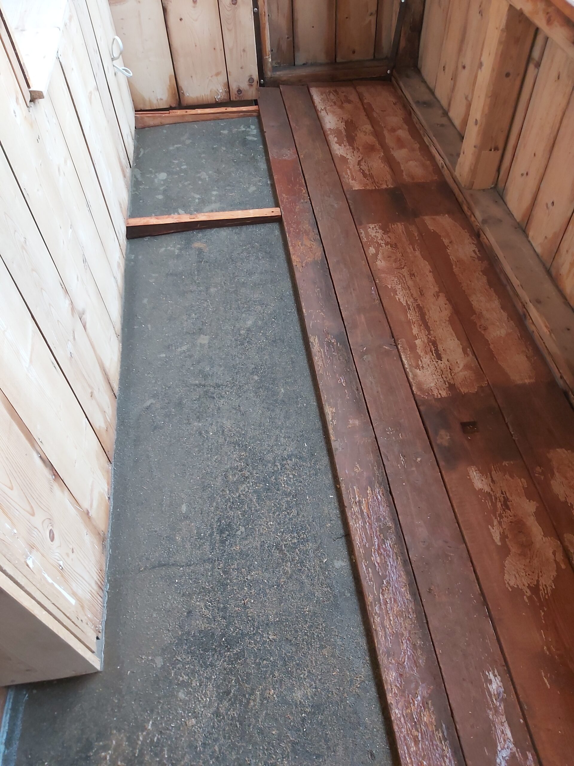 Odsłonięta podłoga balkonu z widoczną warstwą izolacyjną oraz starymi deskami drewnianymi w trakcie prac remontowych.