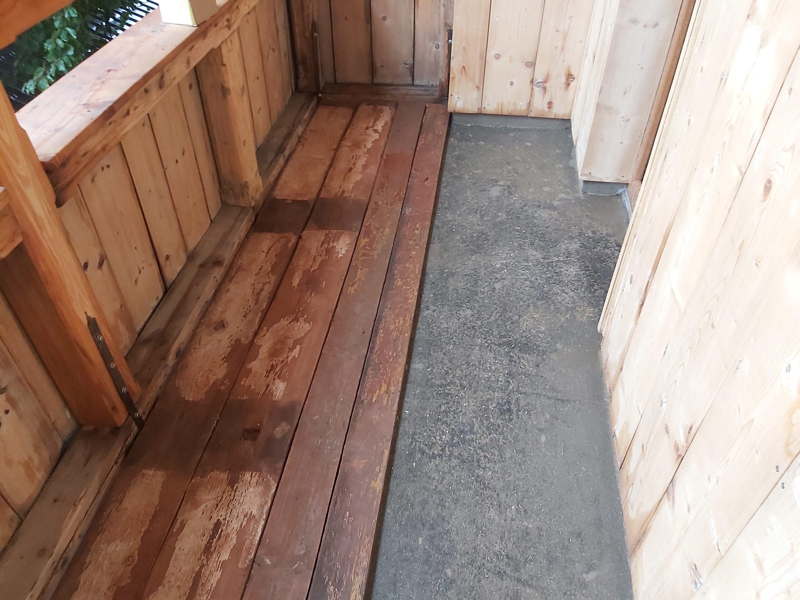 Odsłonięta podłoga balkonu z widocznymi starymi deskami drewnianymi oraz warstwą izolacyjną, przygotowana do dalszych prac remontowych.