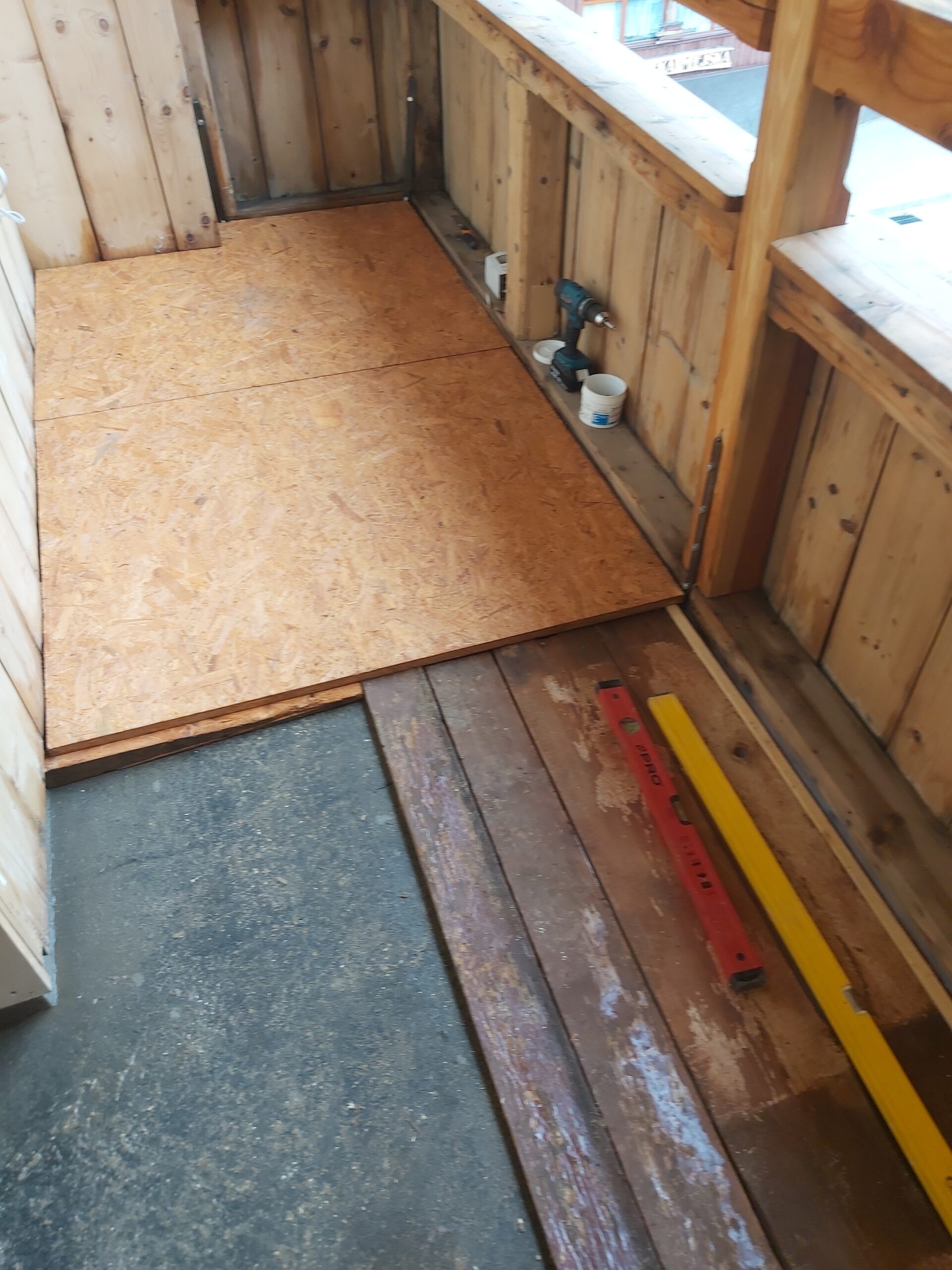 Płyty OSB montowane na podłodze balkonu, częściowo odsłaniające starą drewnianą konstrukcję i warstwę izolacyjną.