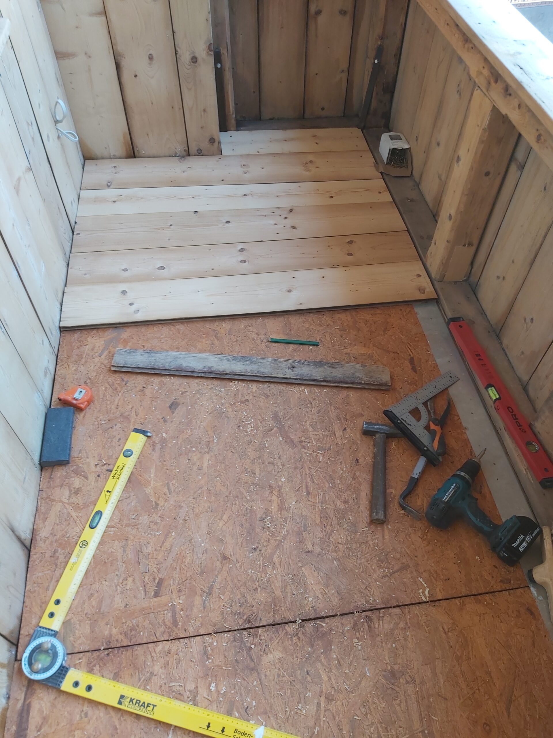 Fragment balkonu w trakcie montażu drewnianej podłogi, widoczne narzędzia stolarskie i częściowo ułożone deski podłogowe.