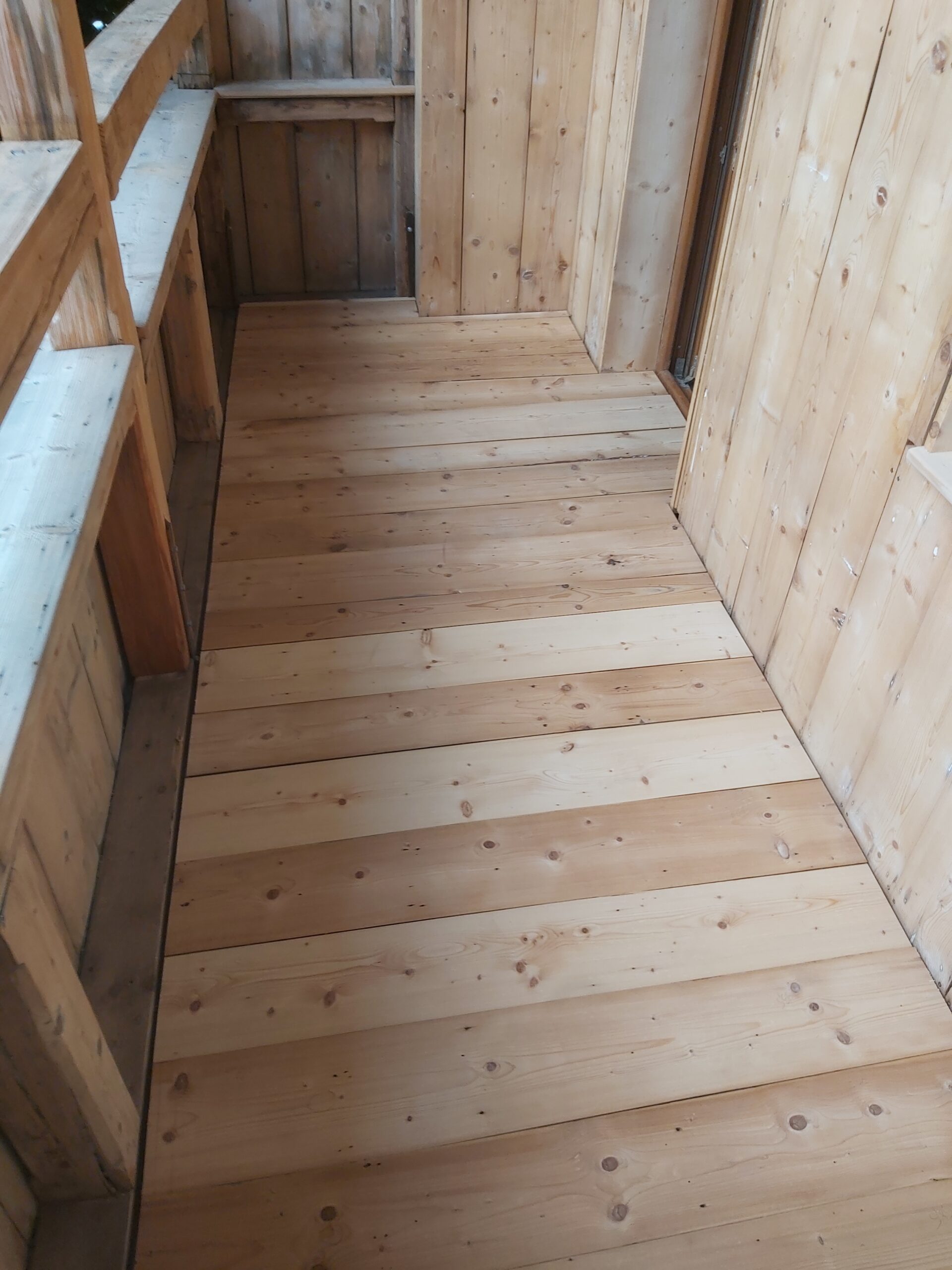 Nowa drewniana podłoga z jasnych desek na balkonie lub ganku, widok od góry, po zakończonych pracach remontowych.