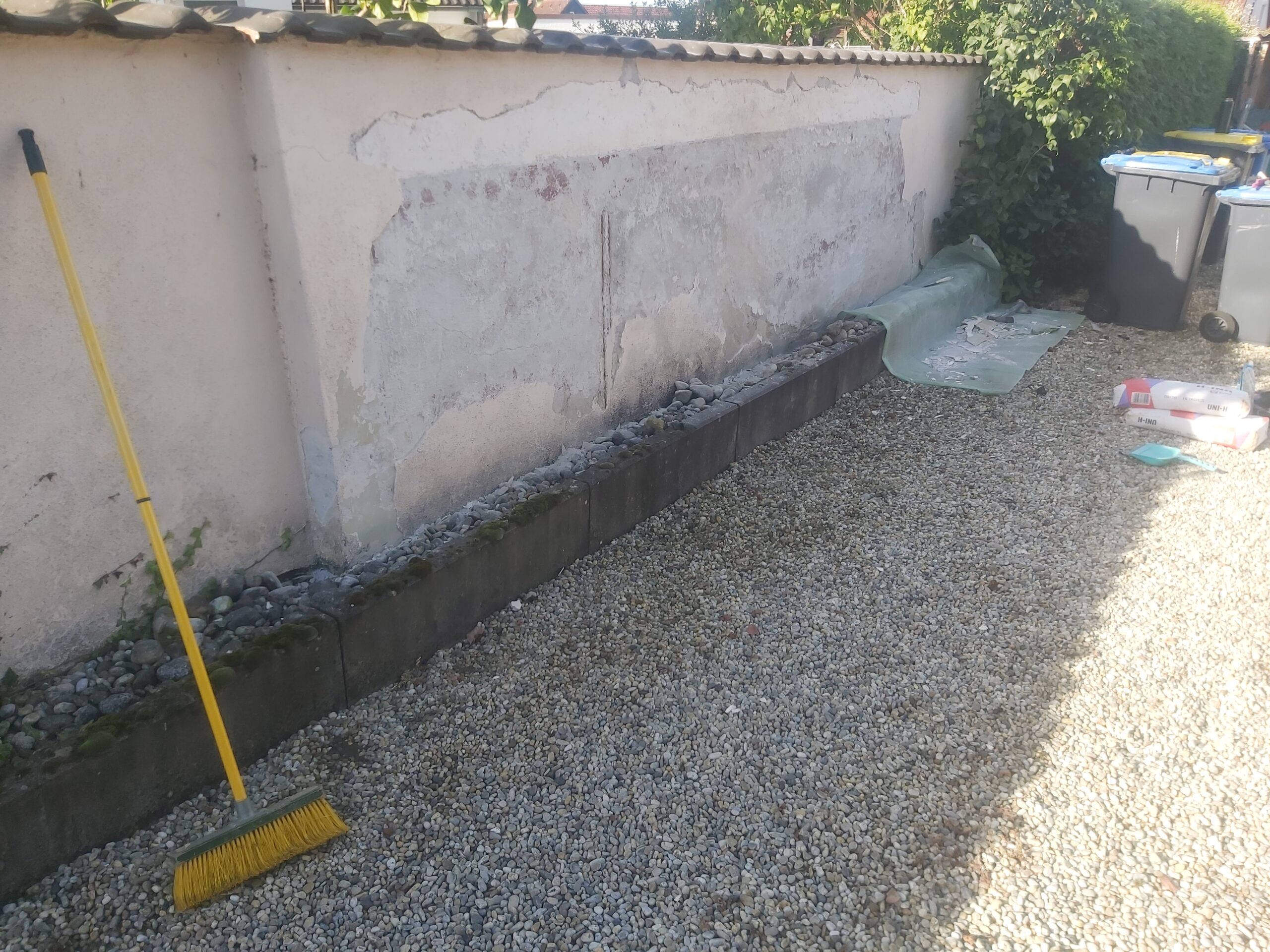 Żwirowa nawierzchnia wzdłuż muru ogrodzeniowego po zakończeniu prac porządkowych, z widocznym obrzeżem betonowym i uporządkowanym terenem wokół posesji.