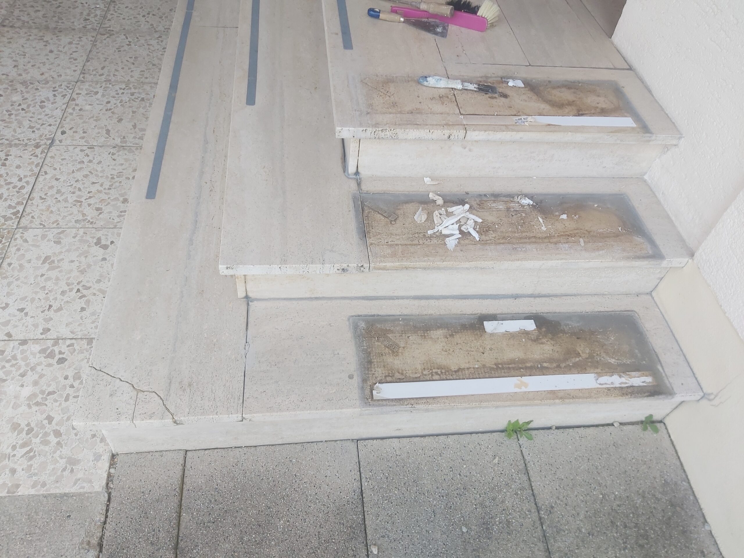 Schody wejściowe w trakcie prac renowacyjnych, z widocznymi uzupełnieniami, narzędziami i przygotowaniem powierzchni do dalszego wykończenia.