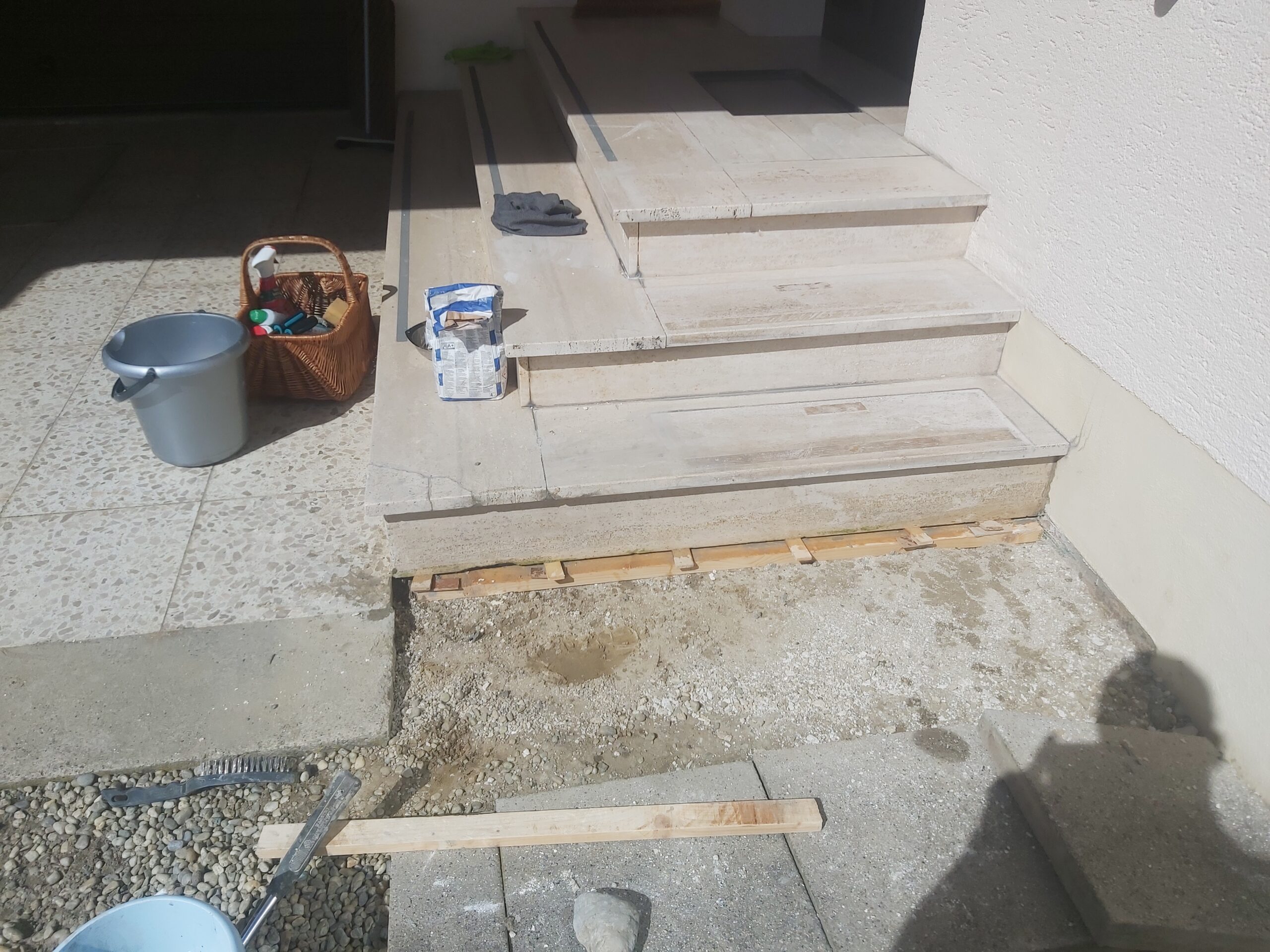 Schody wejściowe w trakcie prac wykończeniowych, z odsłoniętym podłożem przed pierwszym stopniem oraz narzędziami i materiałami przygotowanymi do dalszych etapów.