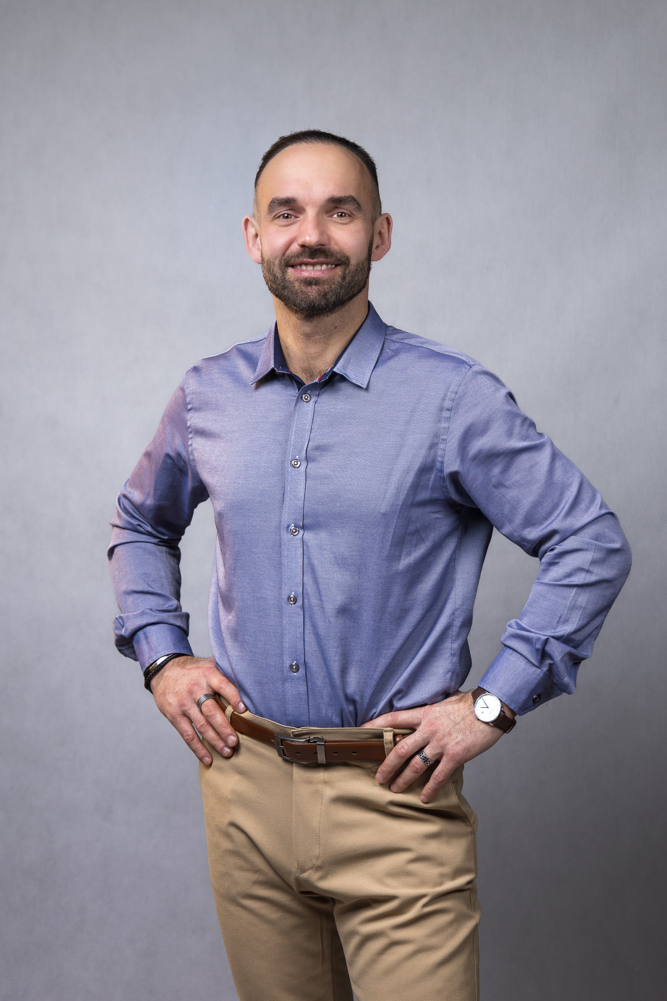 Portret mężczyzny w niebieskiej koszuli i beżowych spodniach na jasnym tle