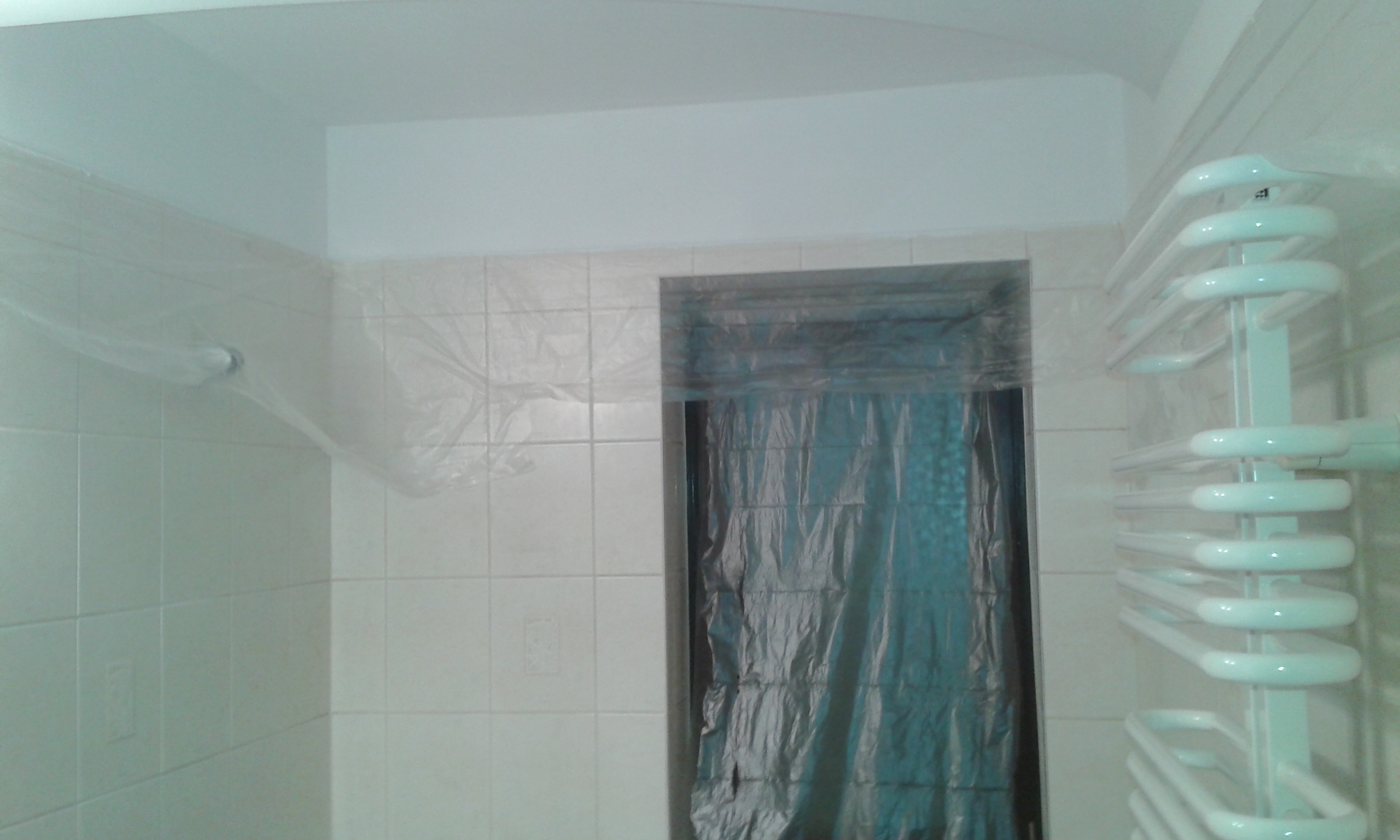 Ściana łazienki z płytkami ceramicznymi i otworem okiennym zabezpieczonym folią ochronną