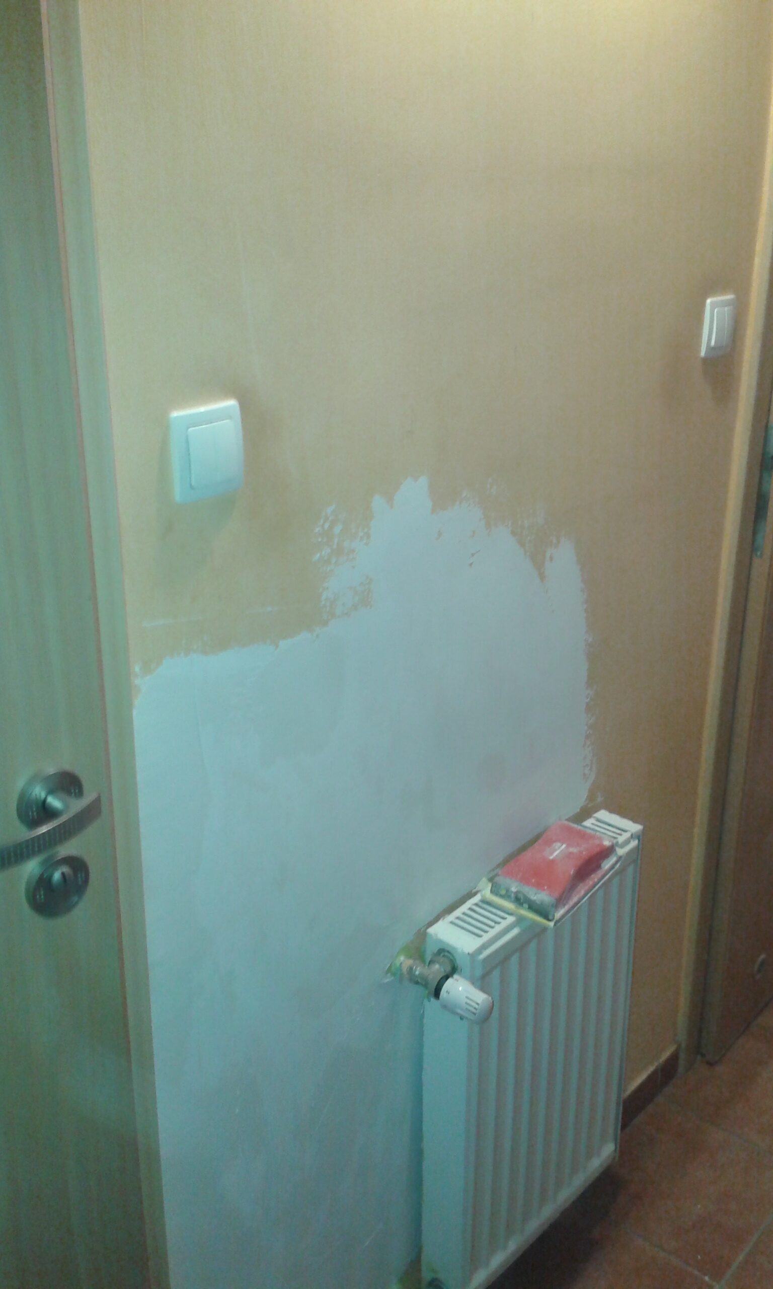 Naprawiany fragment ściany w korytarzu nad grzejnikiem i obok włącznika światła