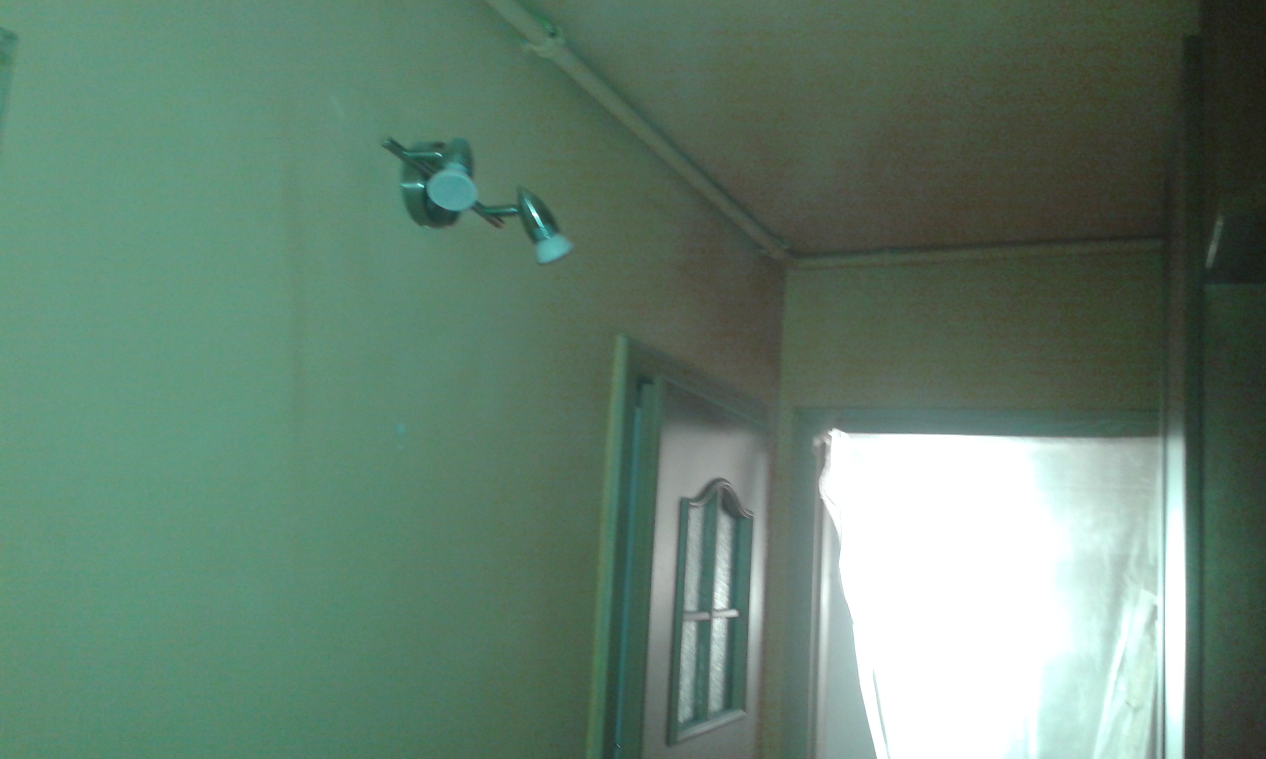 Pęknięcie farby na ścianie w korytarzu nad drzwiami i oprawą oświetleniową