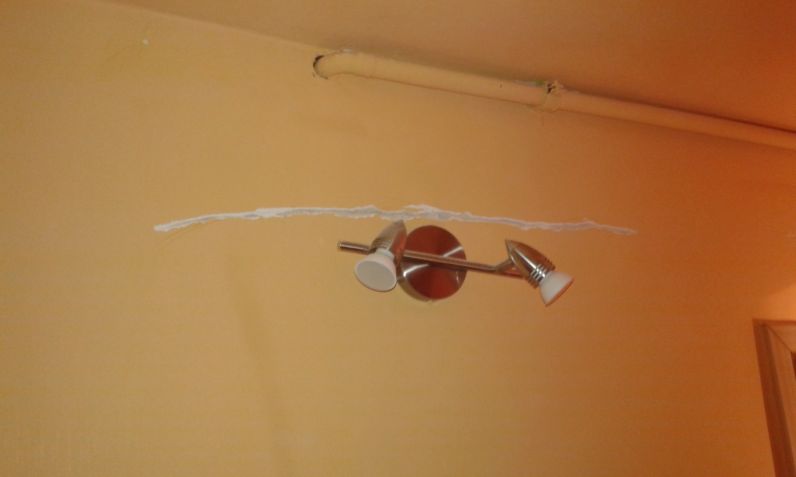 Ścienna lampa punktowa z widoczną pękniętą warstwą farby podczas remontu