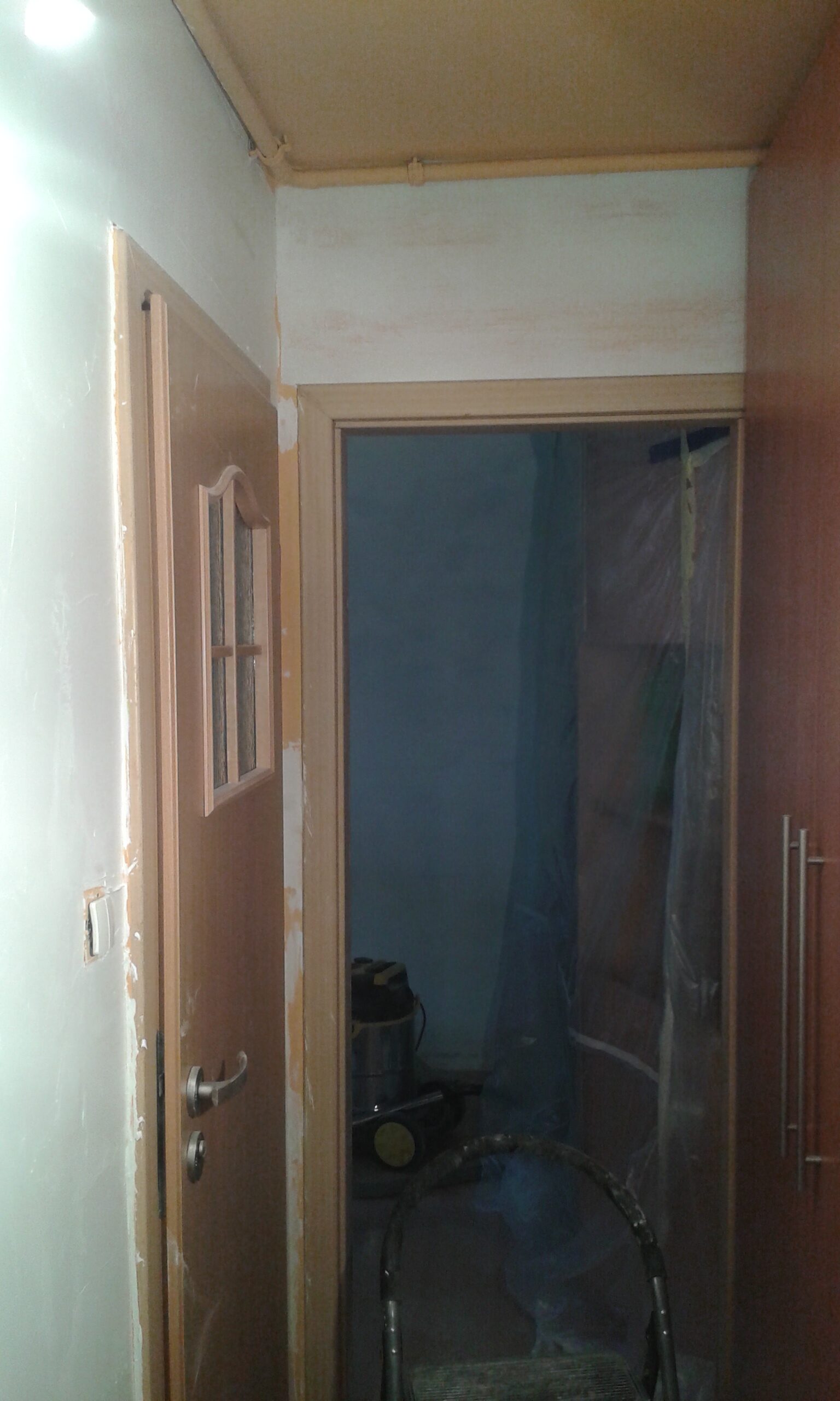 Przejście w korytarzu z drzwiami i widocznymi śladami prac wykończeniowych