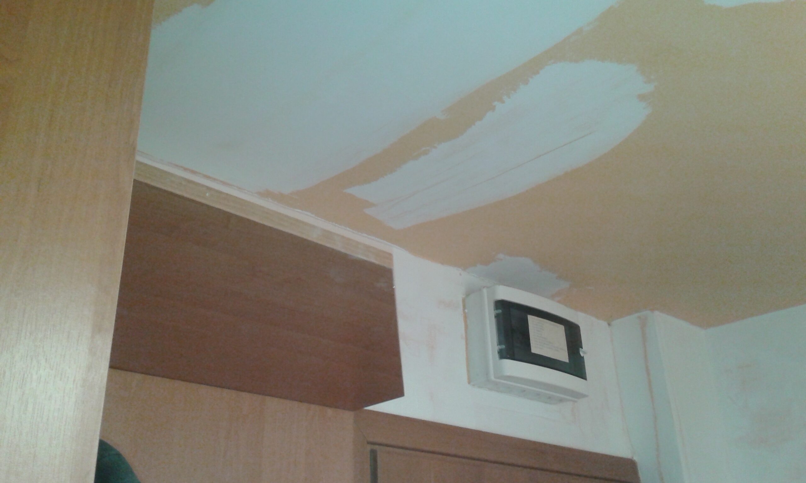 Sufit po szpachlowaniu z widoczną rozdzielnią elektryczną nad szafką