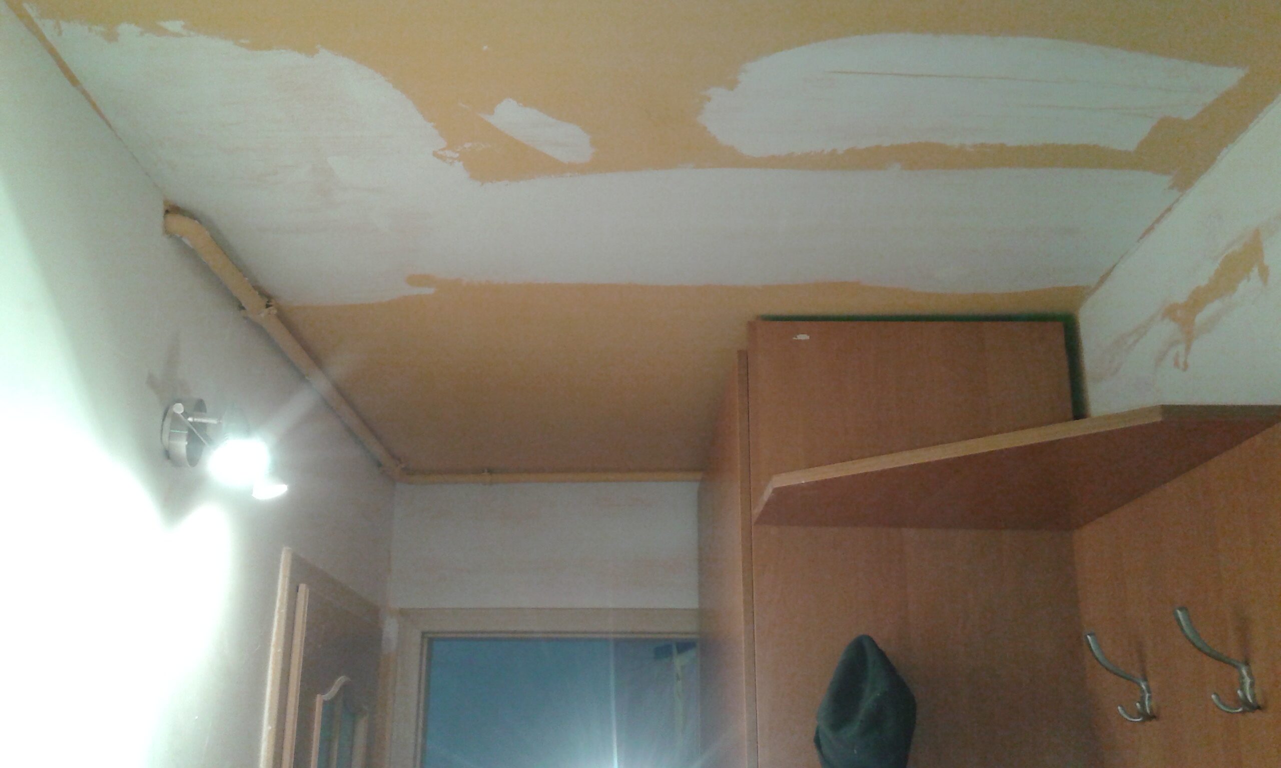 Sufit w pomieszczeniu z widocznymi pasami szpachli oraz szafką ścienną w trakcie remontu