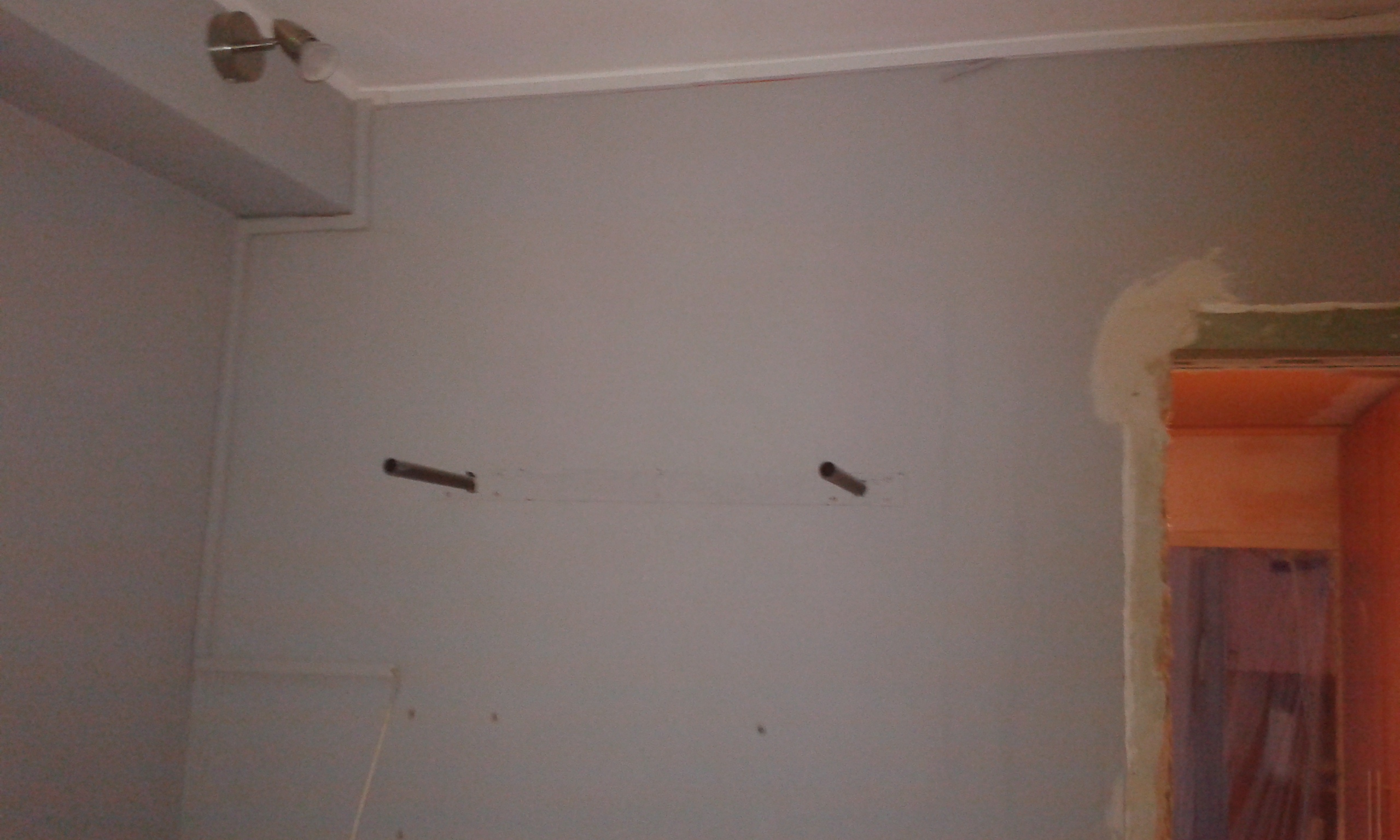 Ściana wewnętrzna z widocznymi otworami montażowymi po demontażu elementów wyposażenia, przygotowana do naprawy i dalszych prac wykończeniowych.