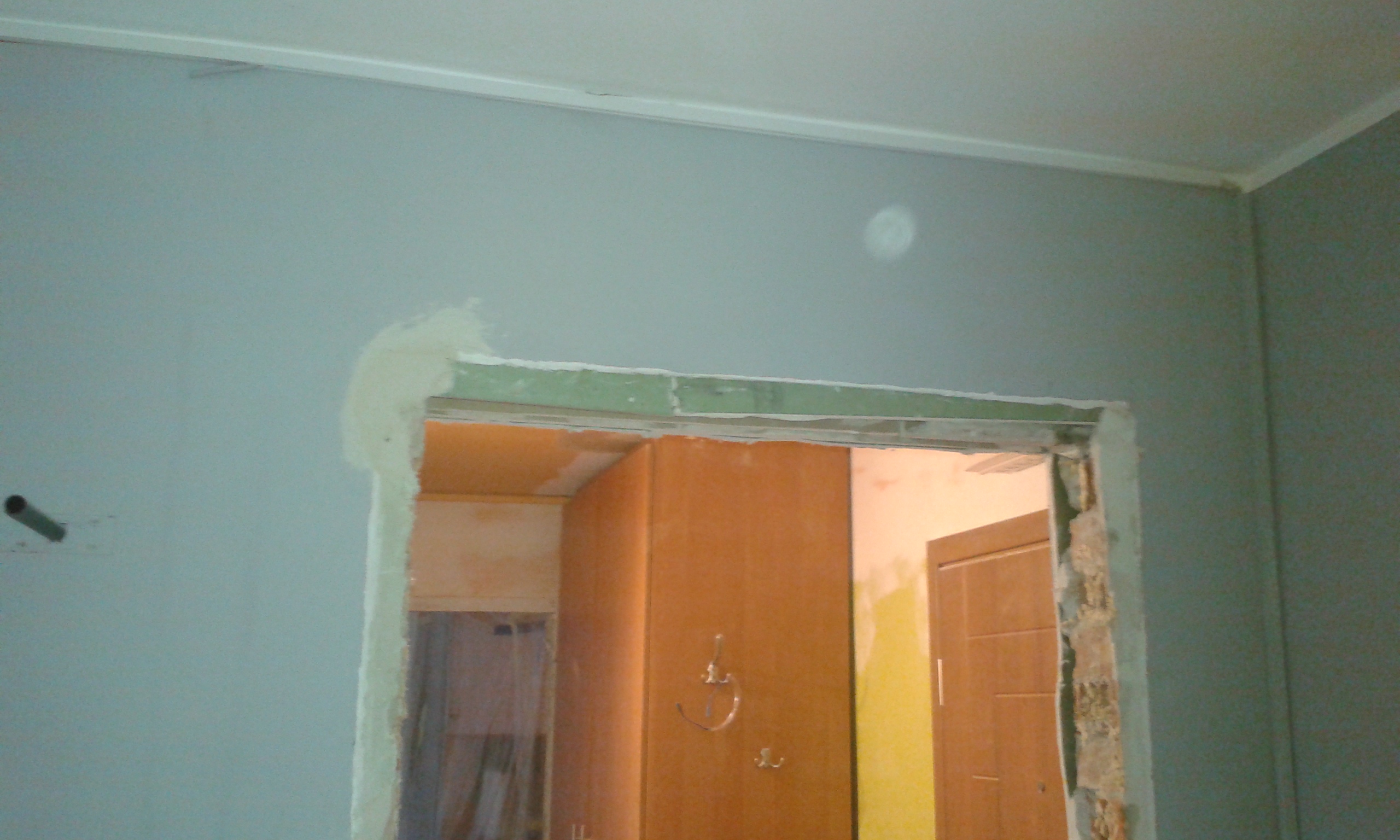 Otwór drzwiowy z widocznymi ubytkami tynku i warstwami montażowymi, przygotowany do osadzenia ościeżnicy i dalszych prac wykończeniowych.