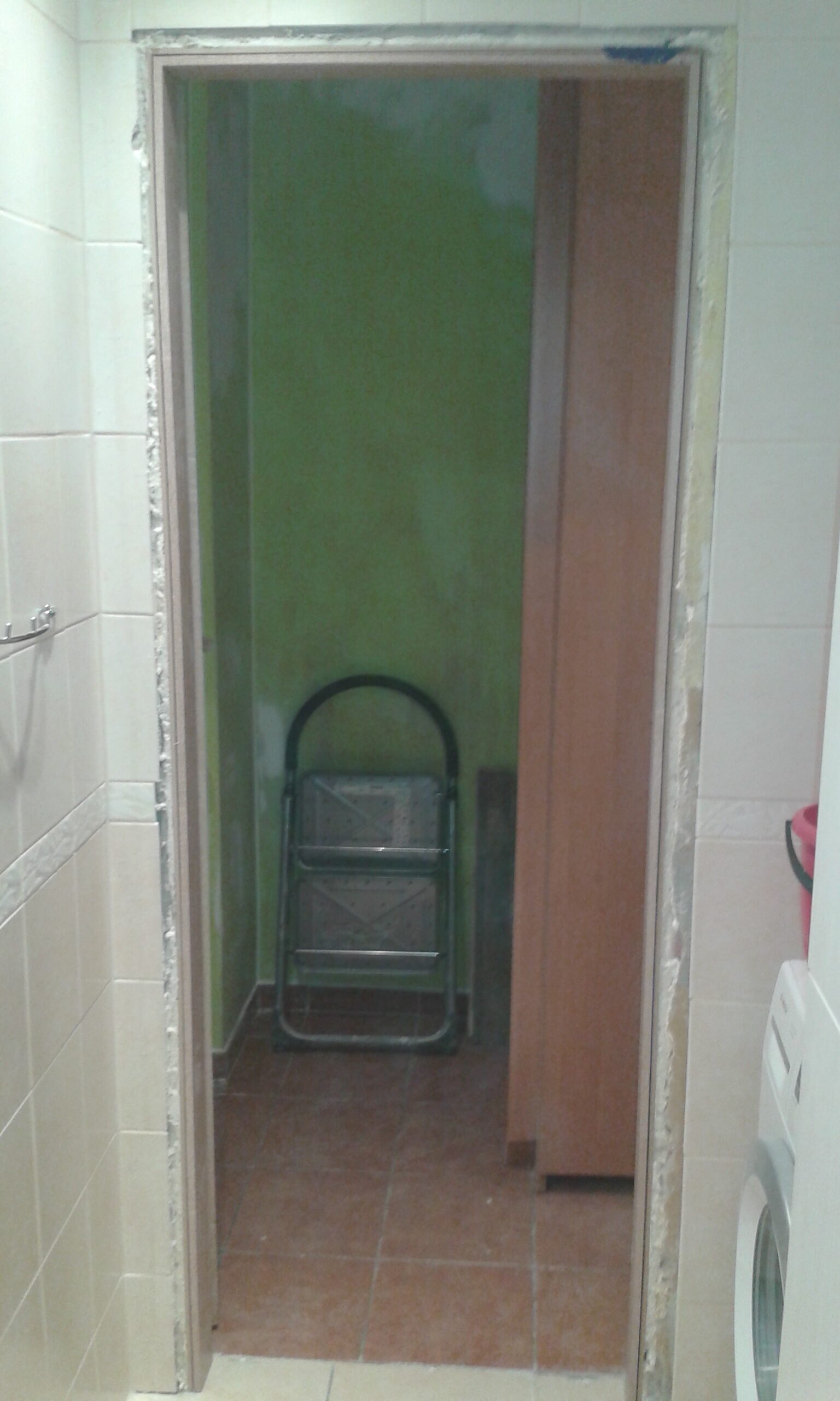 Otwór drzwiowy w łazience po demontażu ościeżnicy, z widocznymi pracami przygotowawczymi przed montażem nowych drzwi.