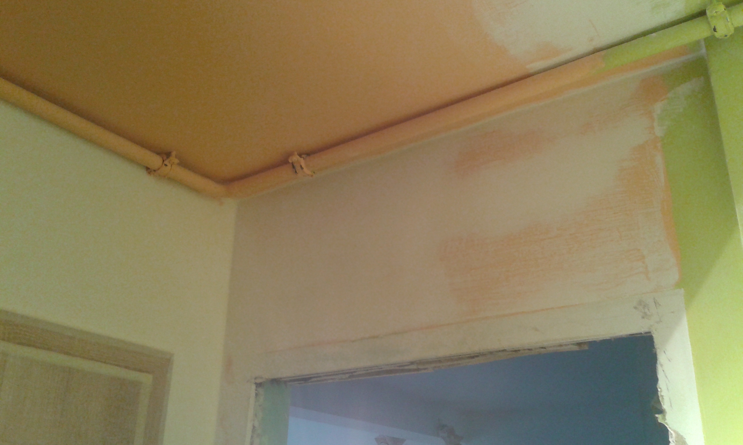 Ściana nad otworem drzwiowym z widocznymi śladami szpachlowania i instalacją prowadzoną przy suficie