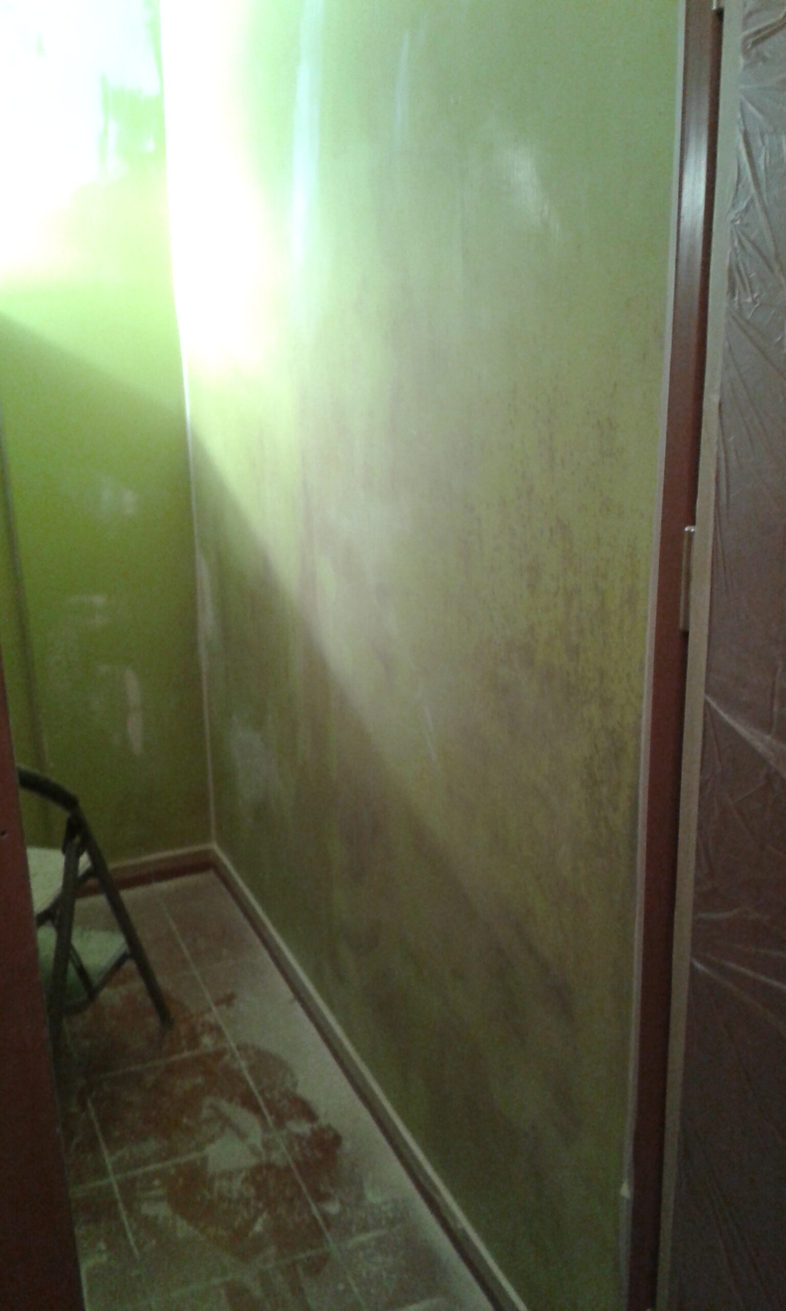 Korytarz z zieloną ścianą w trakcie przygotowania do malowania