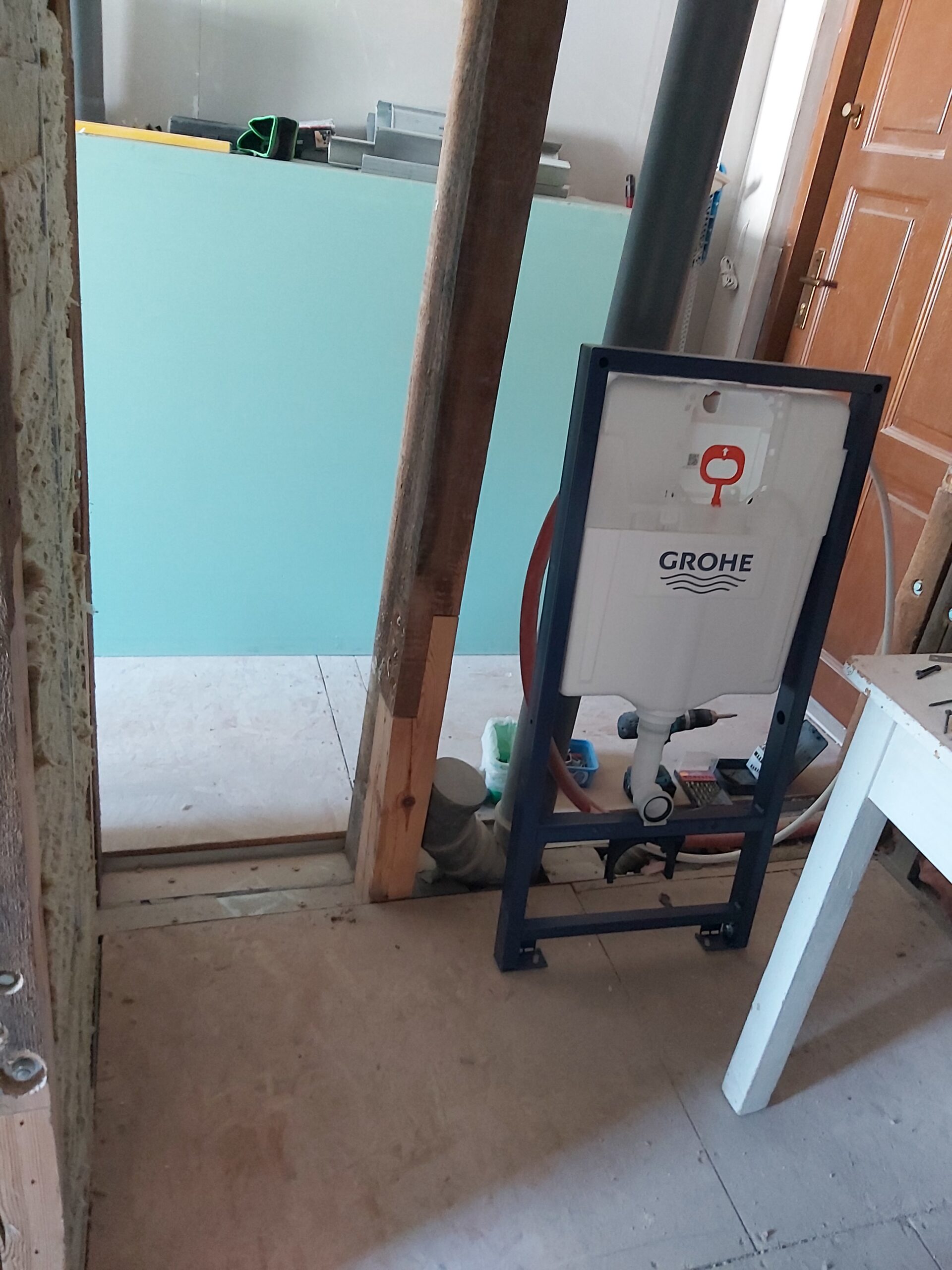 Stelaż podtynkowy WC marki Grohe ustawiony w konstrukcji ściany, widoczny zbiornik spłukujący oraz instalacja kanalizacyjna podczas prac remontowych.