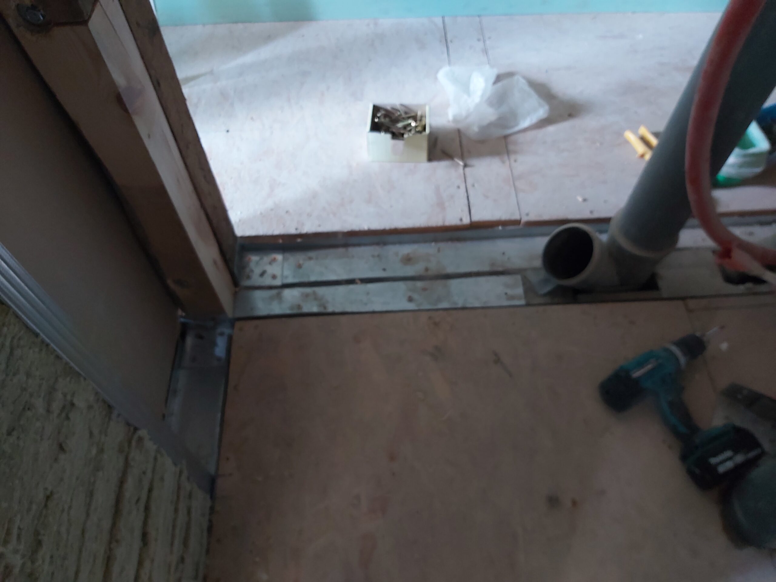 Dolna część konstrukcji ściany działowej pod stelaż WC z widocznymi profilami metalowymi przy podłodze, otworem na rurę kanalizacyjną oraz narzędziami montażowymi podczas prac instalacyjnych.