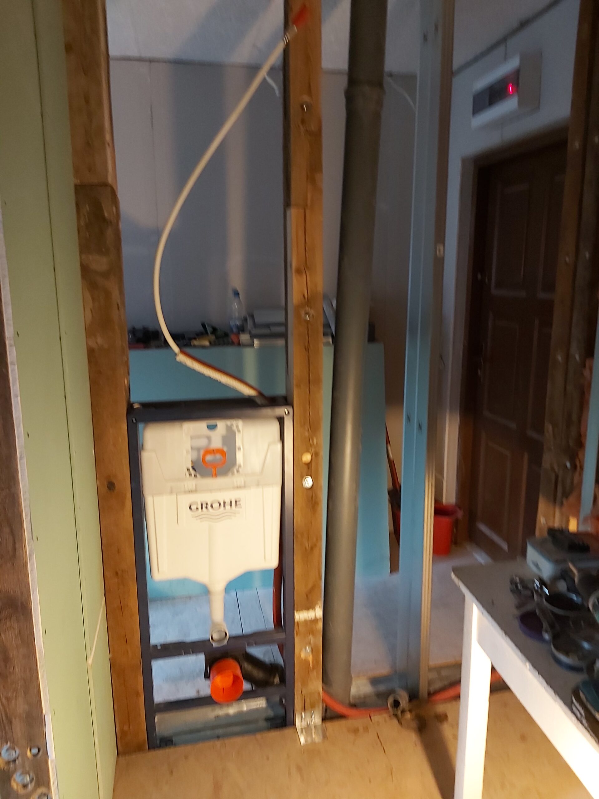 Stelaż WC Grohe zamontowany w konstrukcji ściany działowej, z widoczną instalacją wodną i kanalizacyjną przed zamknięciem płytami g-k.