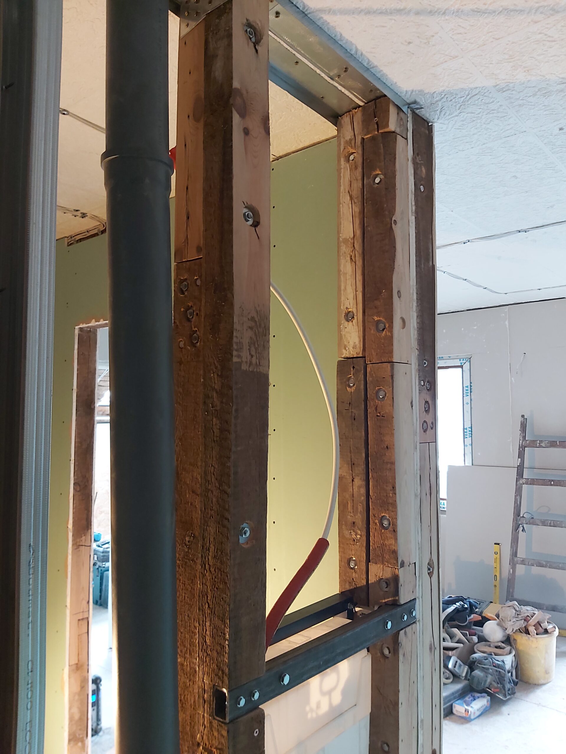 Boczny widok konstrukcji drewniano-metalowej pod zabudowę stelaża WC z widocznymi rurami instalacyjnymi i przygotowaniem pod płyty g-k przed zamknięciem ściany.