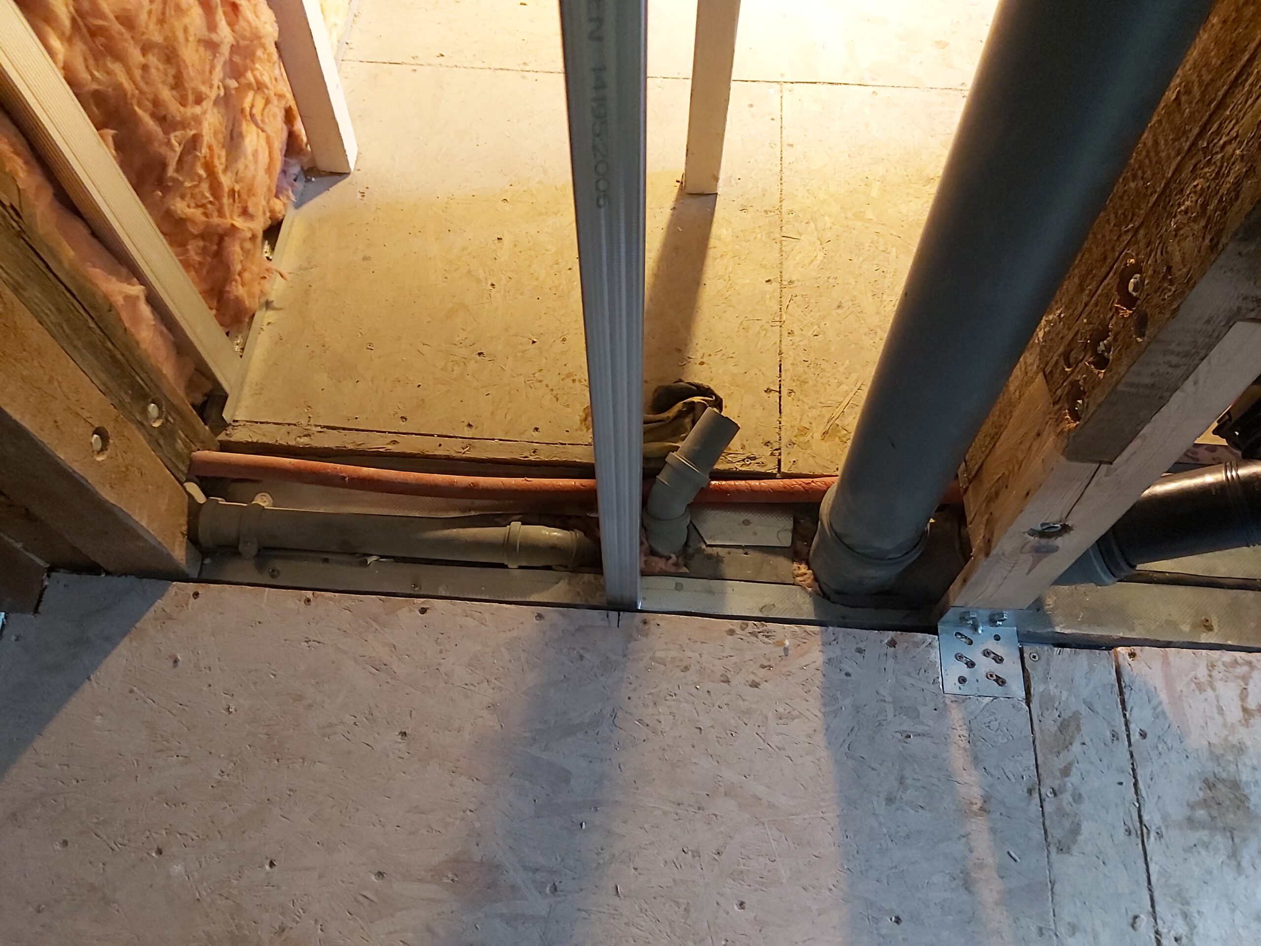 Przejście instalacji kanalizacyjnej i rur w podłodze przy konstrukcji ściany szkieletowej