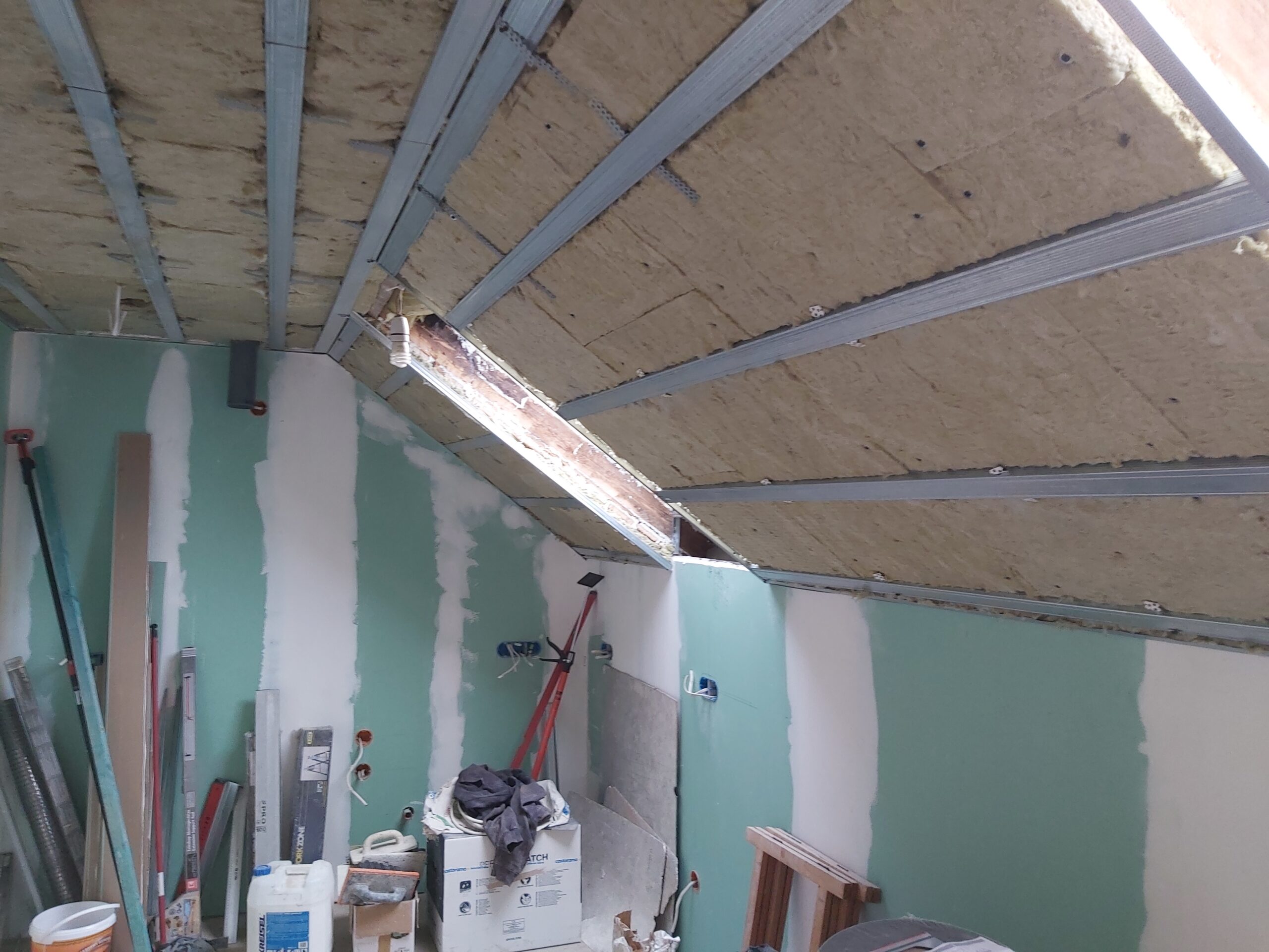 Konstrukcja sufitu poddasza z izolacją i profilami stalowymi podczas prac remontowych