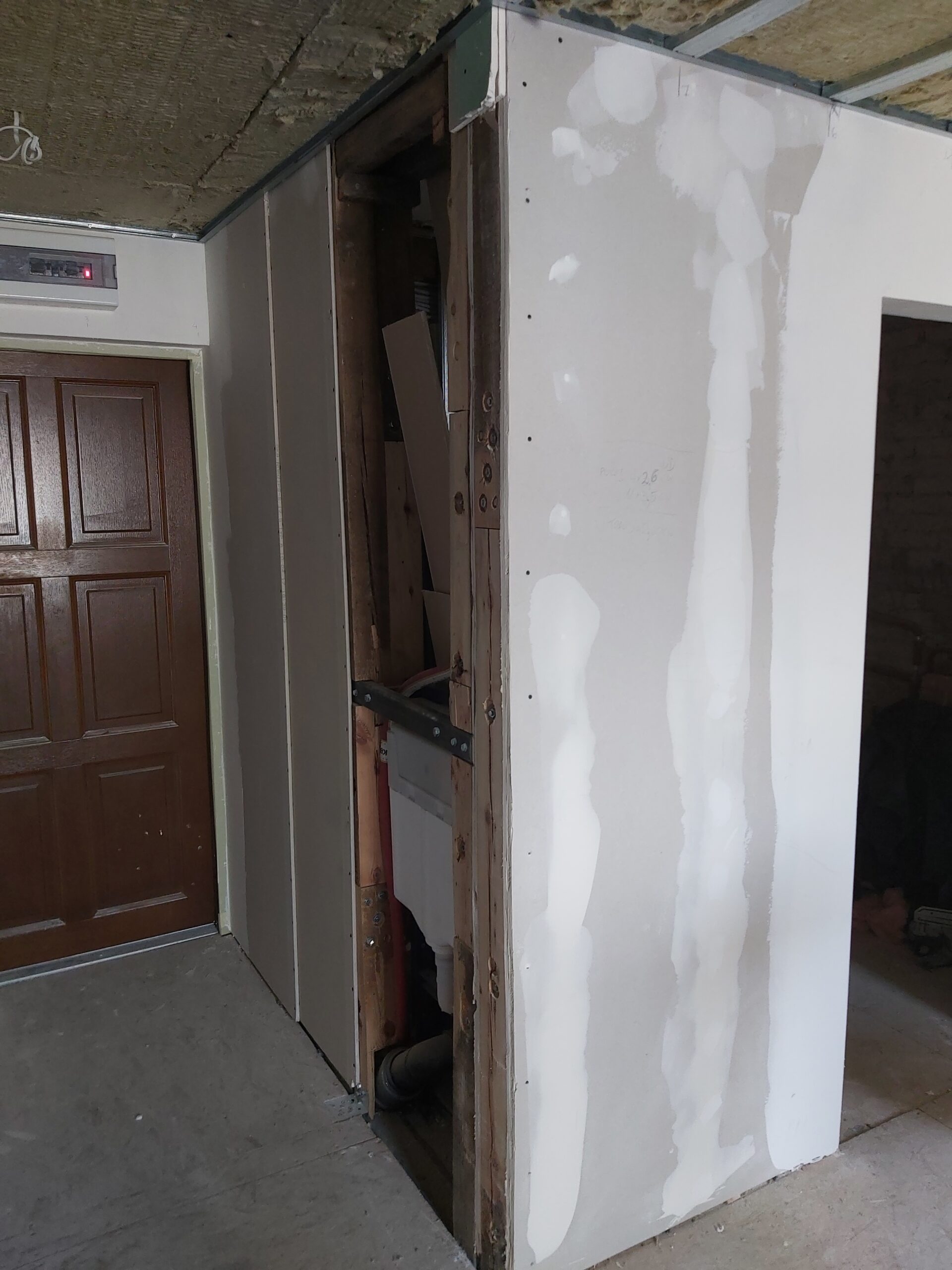 Zabudowa z płyt gipsowo-kartonowych w trakcie montażu, widoczna konstrukcja i instalacje wewnątrz ściany