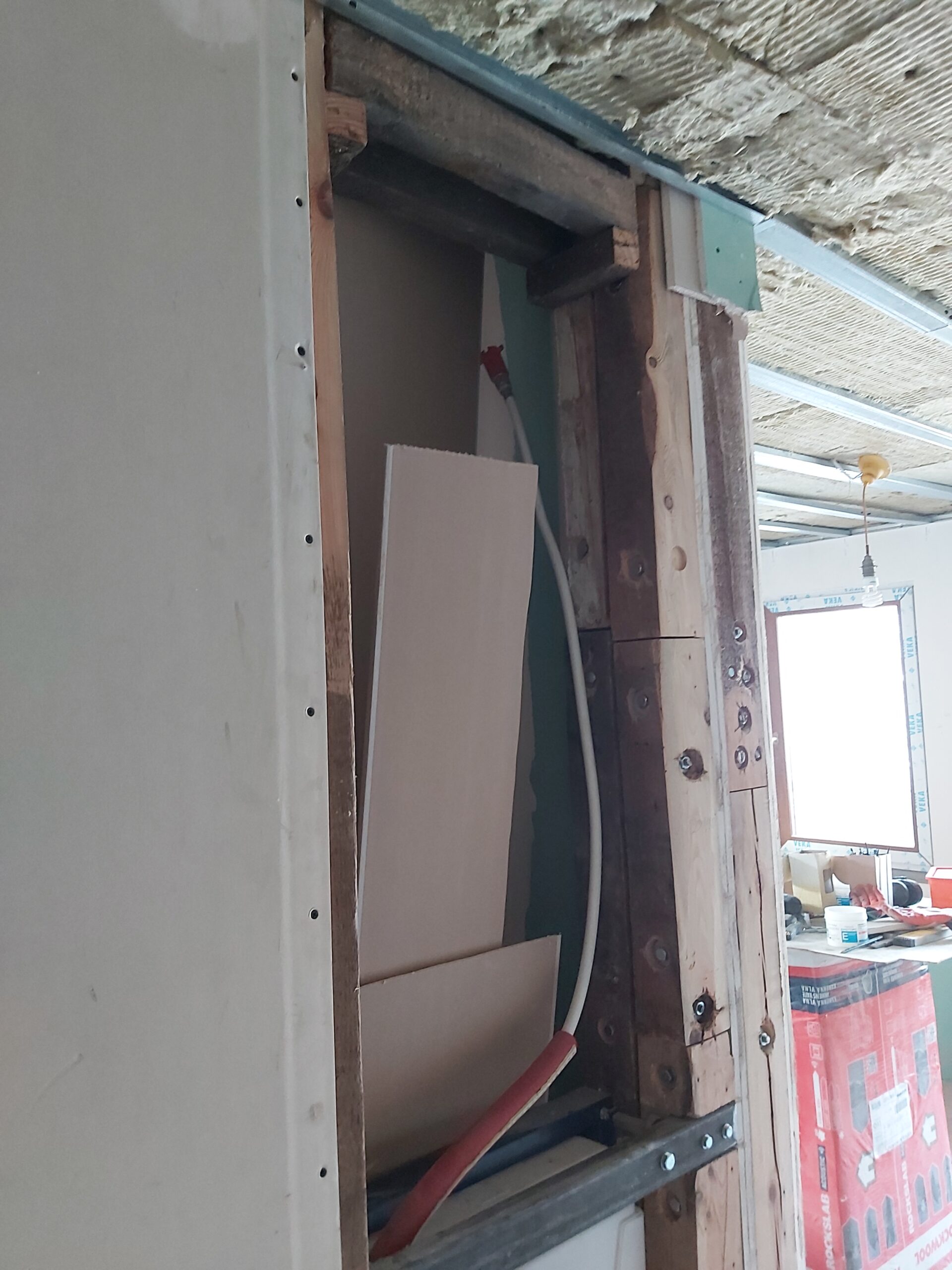 Otwór w ścianie szkieletowej z widoczną konstrukcją drewnianą, instalacją i przygotowaniem pod zabudowę g-k