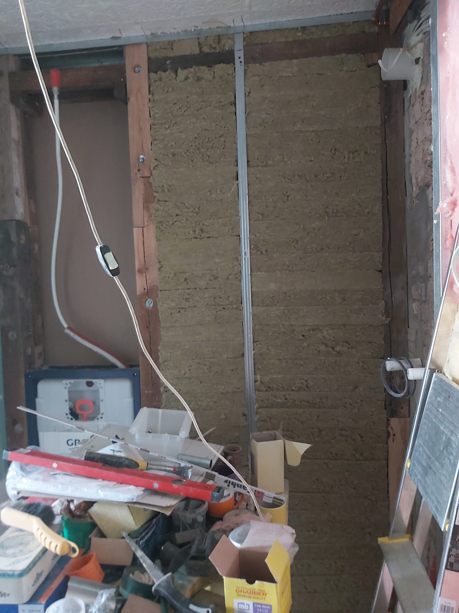 Ściana szkieletowa z wypełnieniem izolacyjnym i elementami instalacji przed montażem płyt g-k