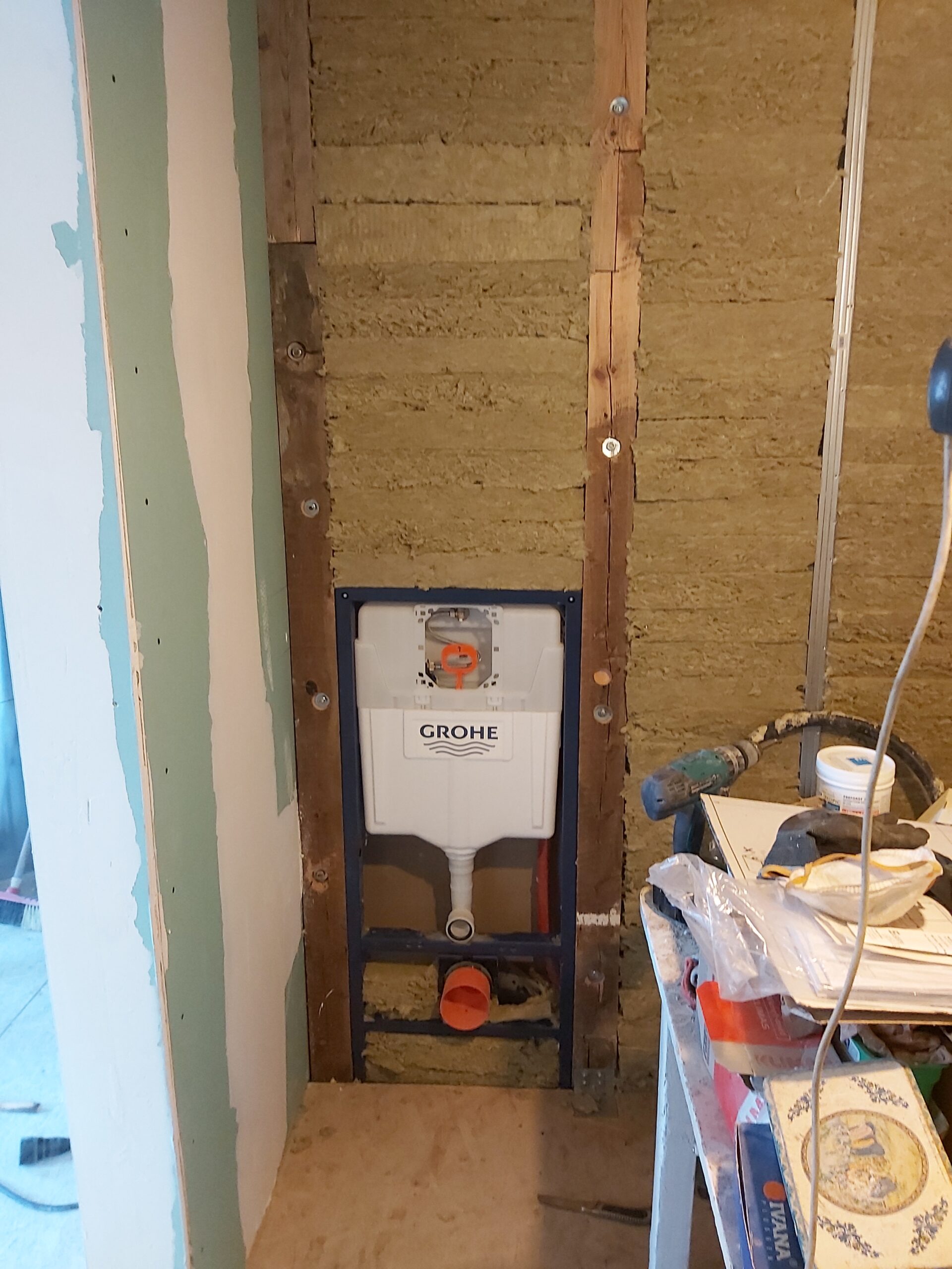 Podtynkowy stelaż WC Grohe zamontowany w ścianie, z widoczną izolacją z wełny mineralnej i konstrukcją drewnianą przed wykonaniem zabudowy w trakcie remontu łazienki.