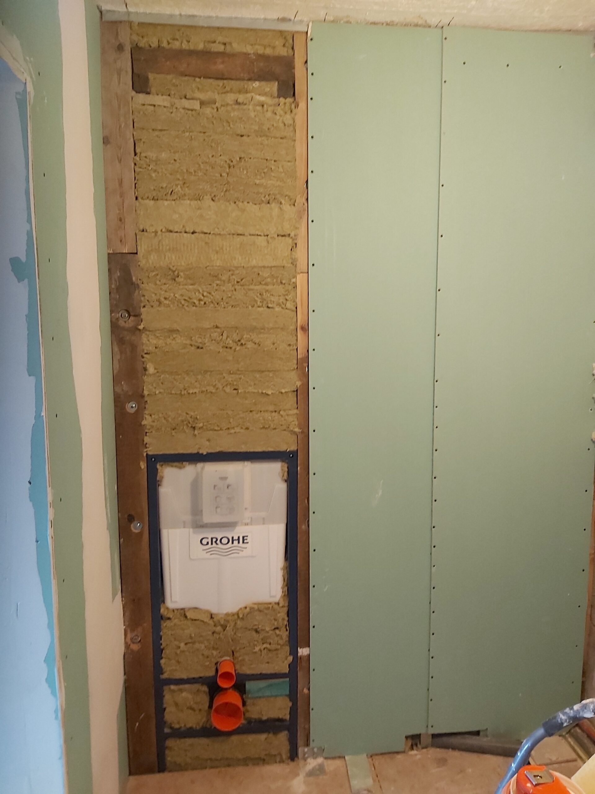 Częściowo zabudowany stelaż podtynkowy WC Grohe, widoczna izolacja z wełny mineralnej oraz montaż płyty g-k w trakcie remontu łazienki.