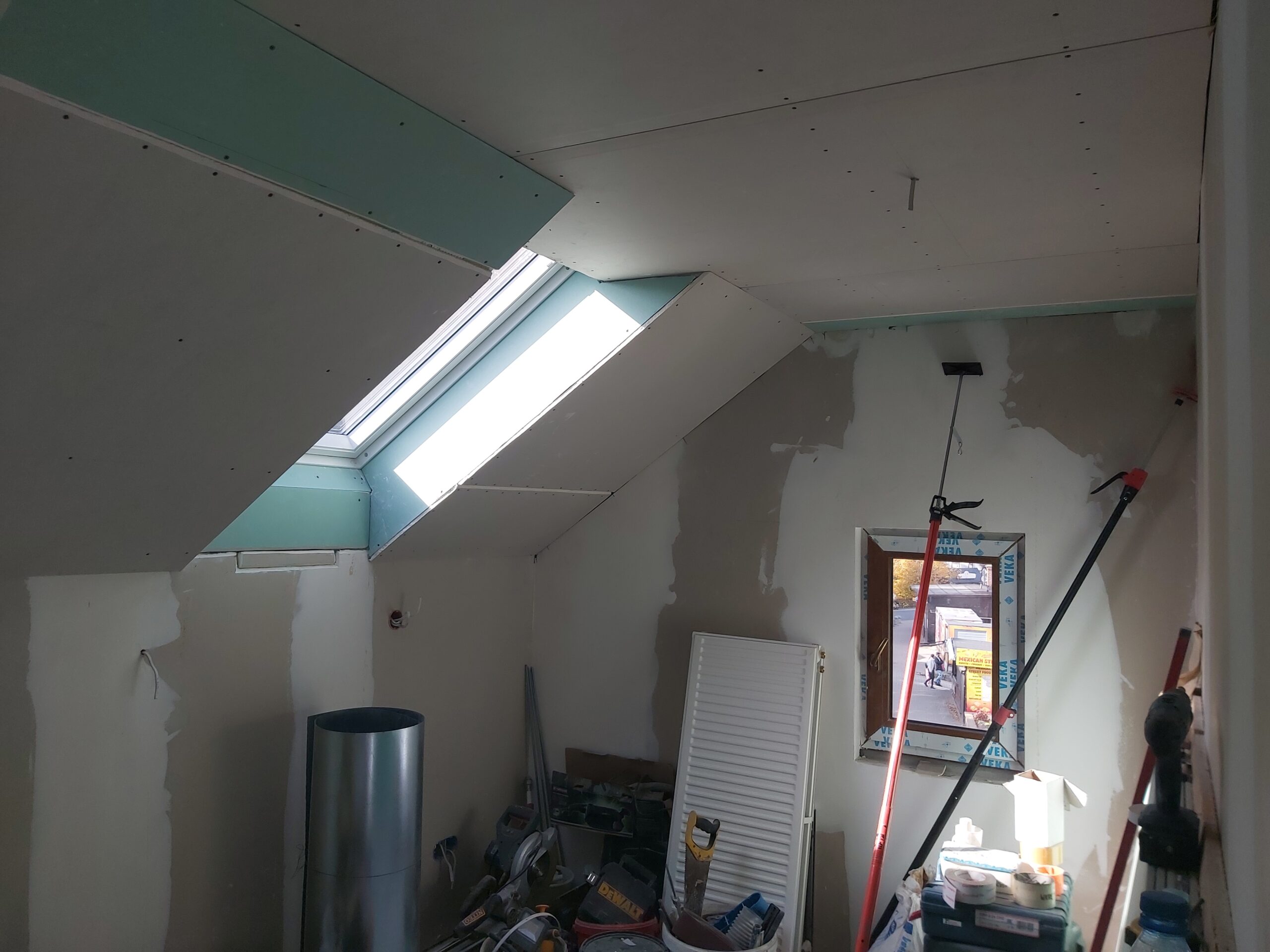 Zabudowa poddasza z oknem dachowym, sufit z płyt gipsowo-kartonowych oraz ściany w trakcie szpachlowania