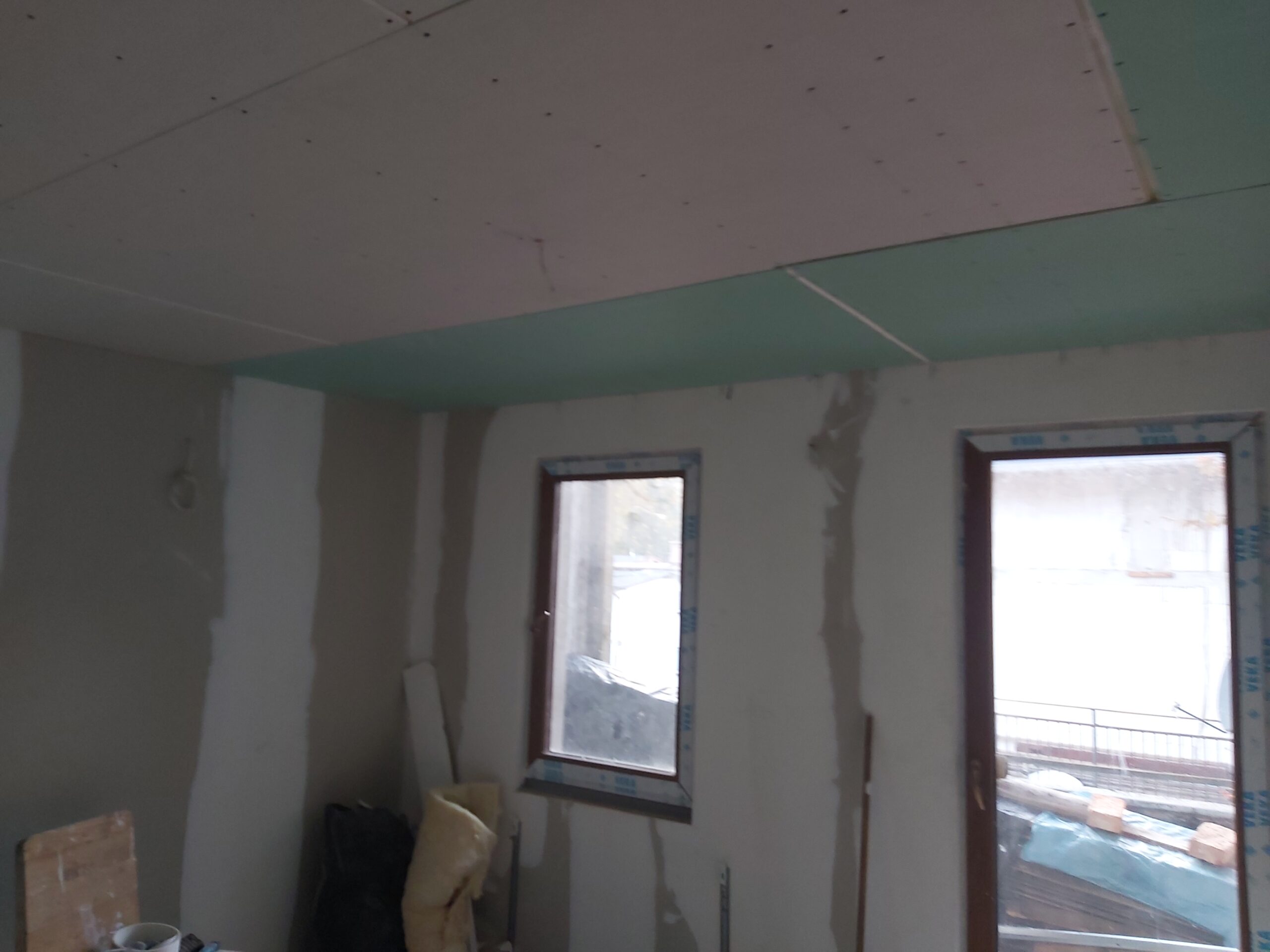 Pomieszczenie w trakcie remontu – sufit z płyt gipsowo-kartonowych oraz ściany przygotowane do szpachlowania, widoczne okna
