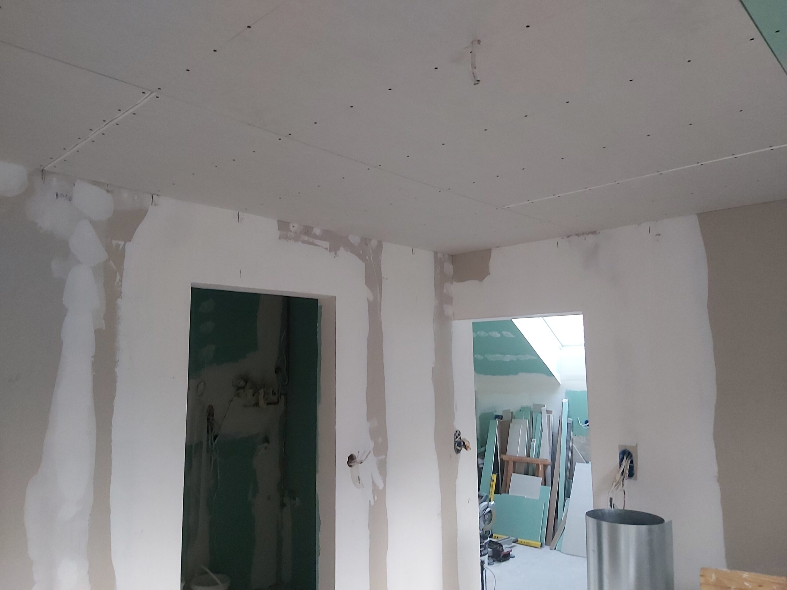 Pomieszczenie w trakcie remontu z zabudową gipsowo-kartonową, wyszpachlowanymi łączeniami i otworami drzwiowymi